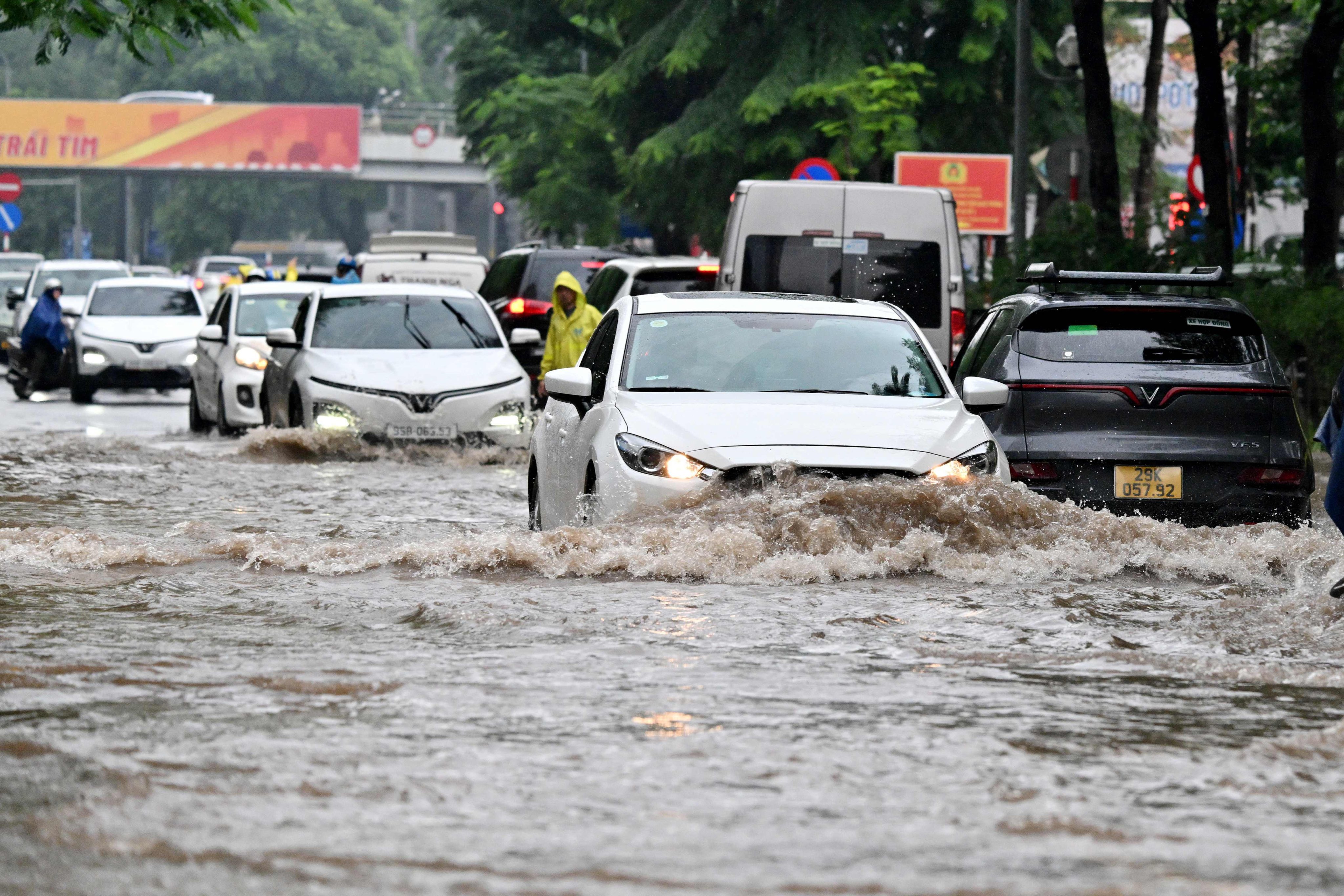 Cars drive along a flooded street in Hanoi on Thursday. Photo: AFP