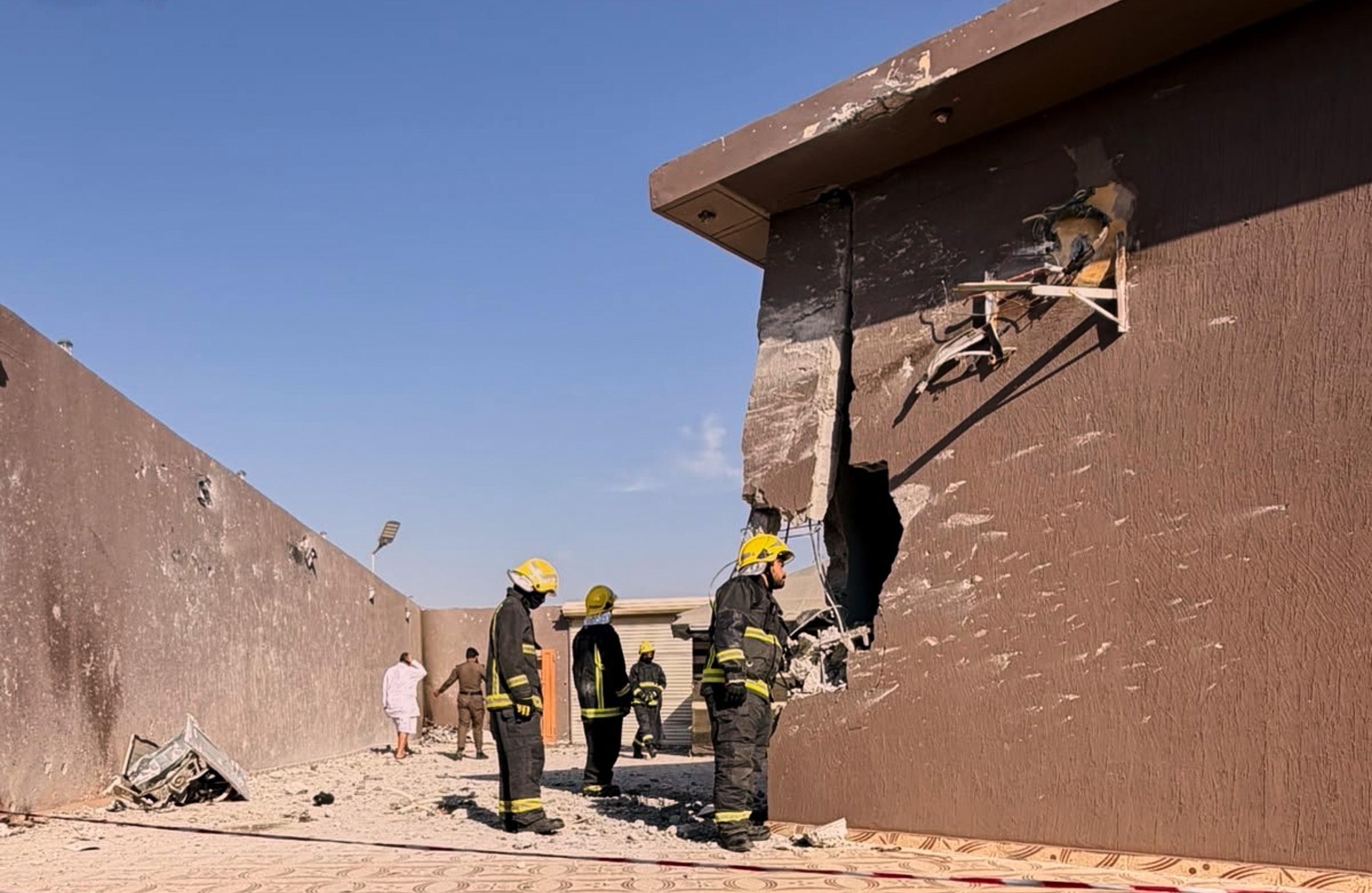 Firefighters inspect damage to a building caused by falling debris from a reported Houthi drone intercepted over Taif province, western Saudi Arabia, on Thursday. Photo: Saudi Press Agency / AP