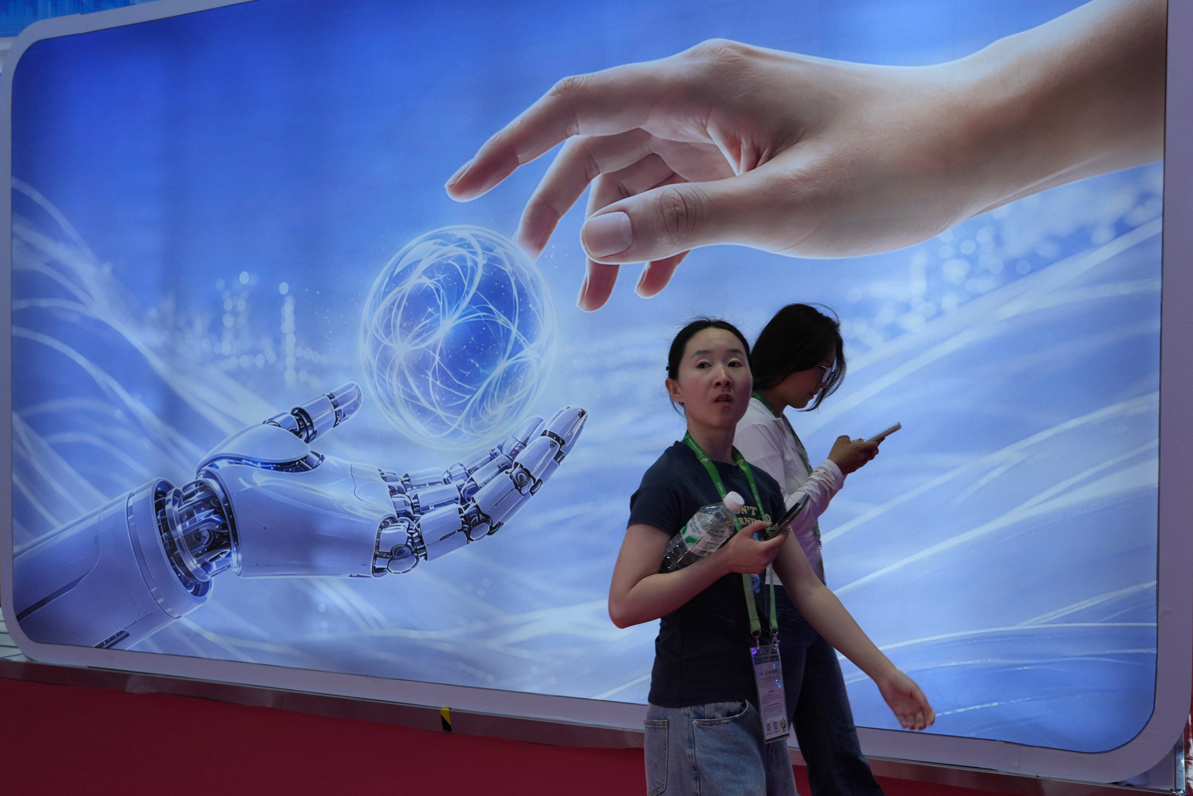 Visitors walk past a display depicting AI and a human hand at the China International Supply Chain Expo in Beijing in June. Photo: AP