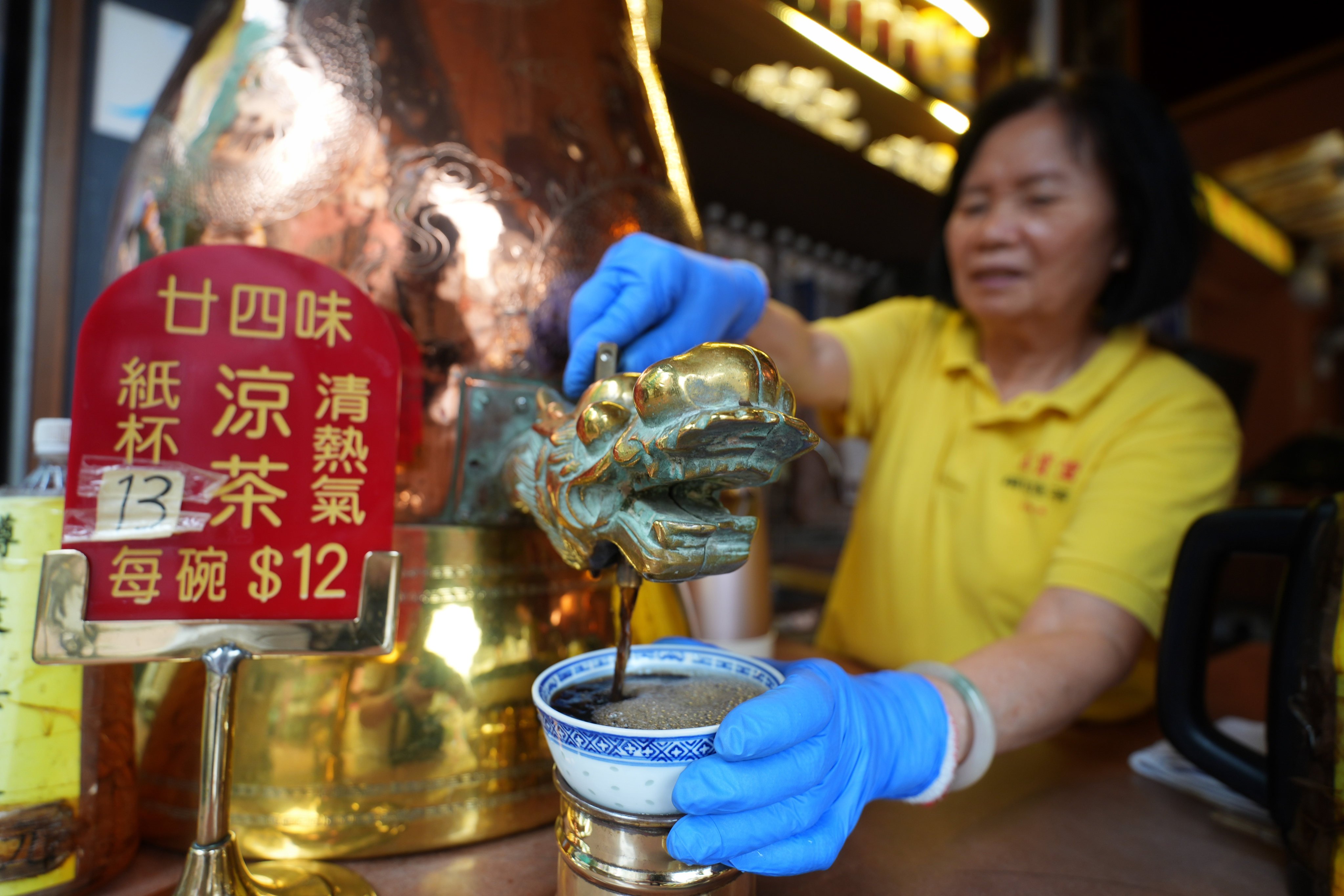 A staff member fills bowls with herbal tea known as leung cha (“cooling tea”) from a giant copper pot at Pak Po Tong on Temple Street in Hong Kong. Photo: Elson Li