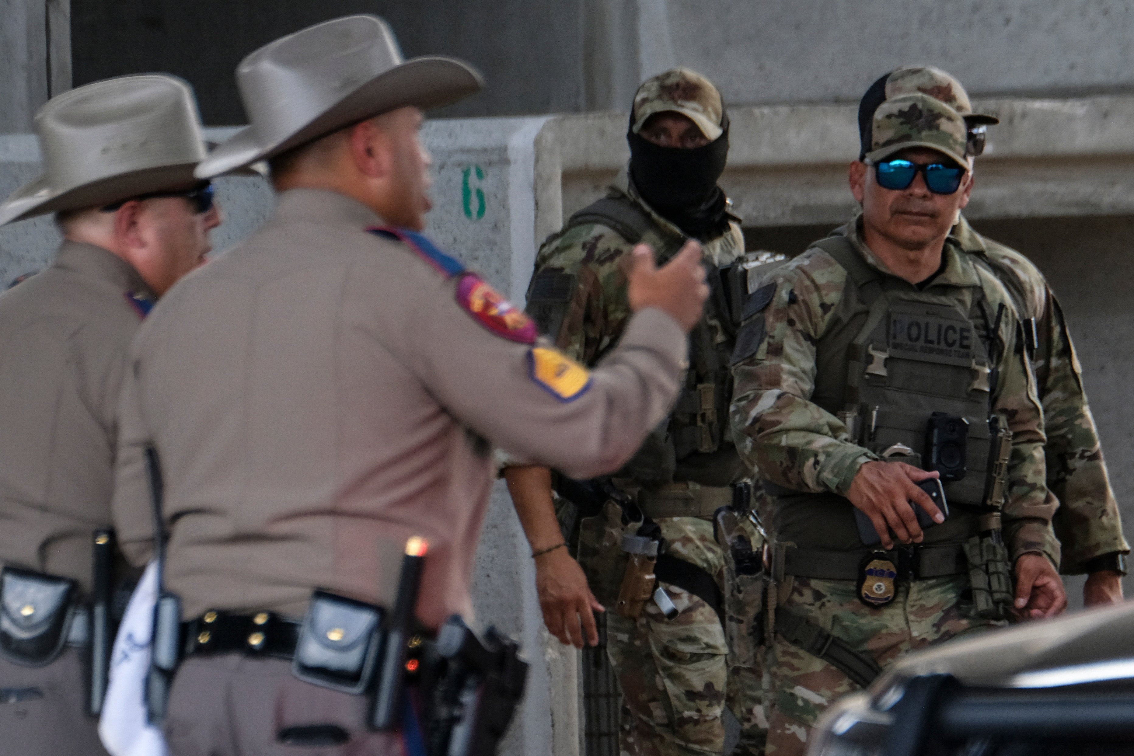 Authorities stand near the scene where a man was shot in his car by an ICE officer on Sunday. Photo: AP