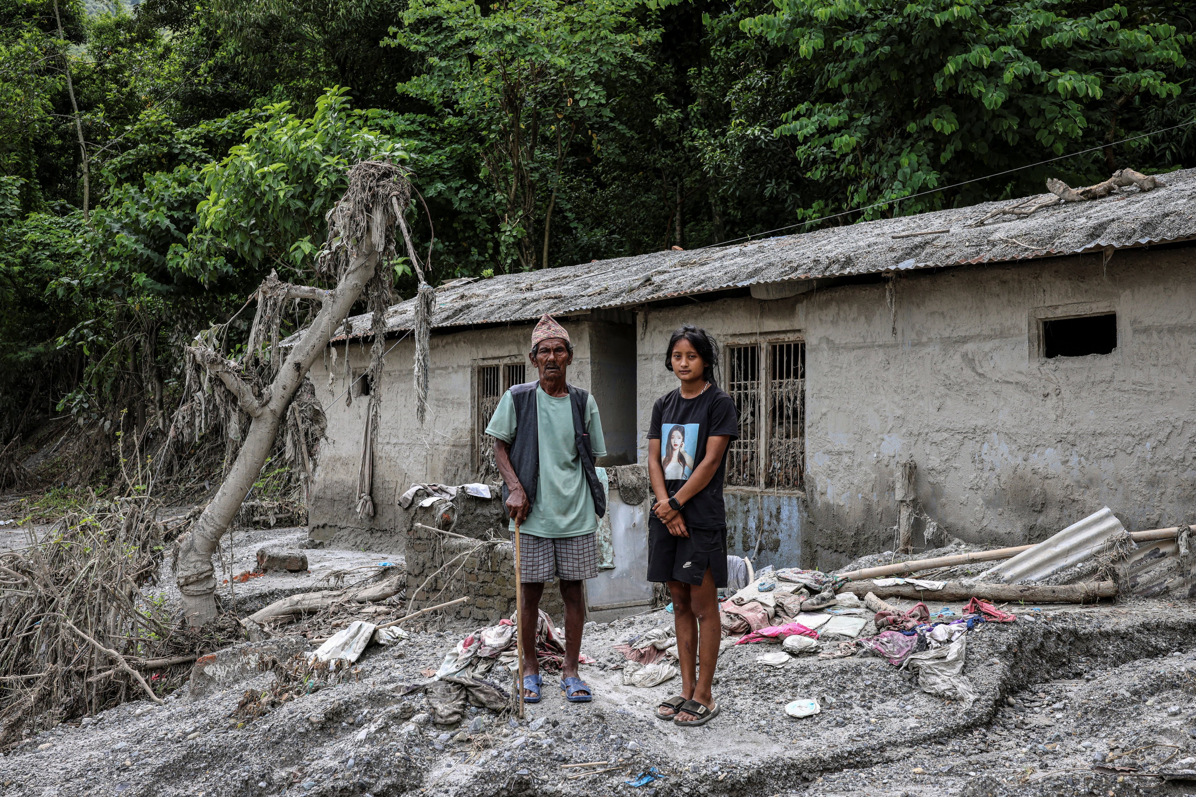 Sachita Rai, 19, and her grandfather Man Bahadur Rai, 80, stand outside their home after thick mud flooded the interior of the structure in Ratamate, Nuwakot district, Nepal. Sachita said she was helping her grandfather on a vegetable farm when floodwaters arrived and rushed to bring him to safety. “I risked my life to save my 80-year-old grandfather,” she said. Photo: Reuters