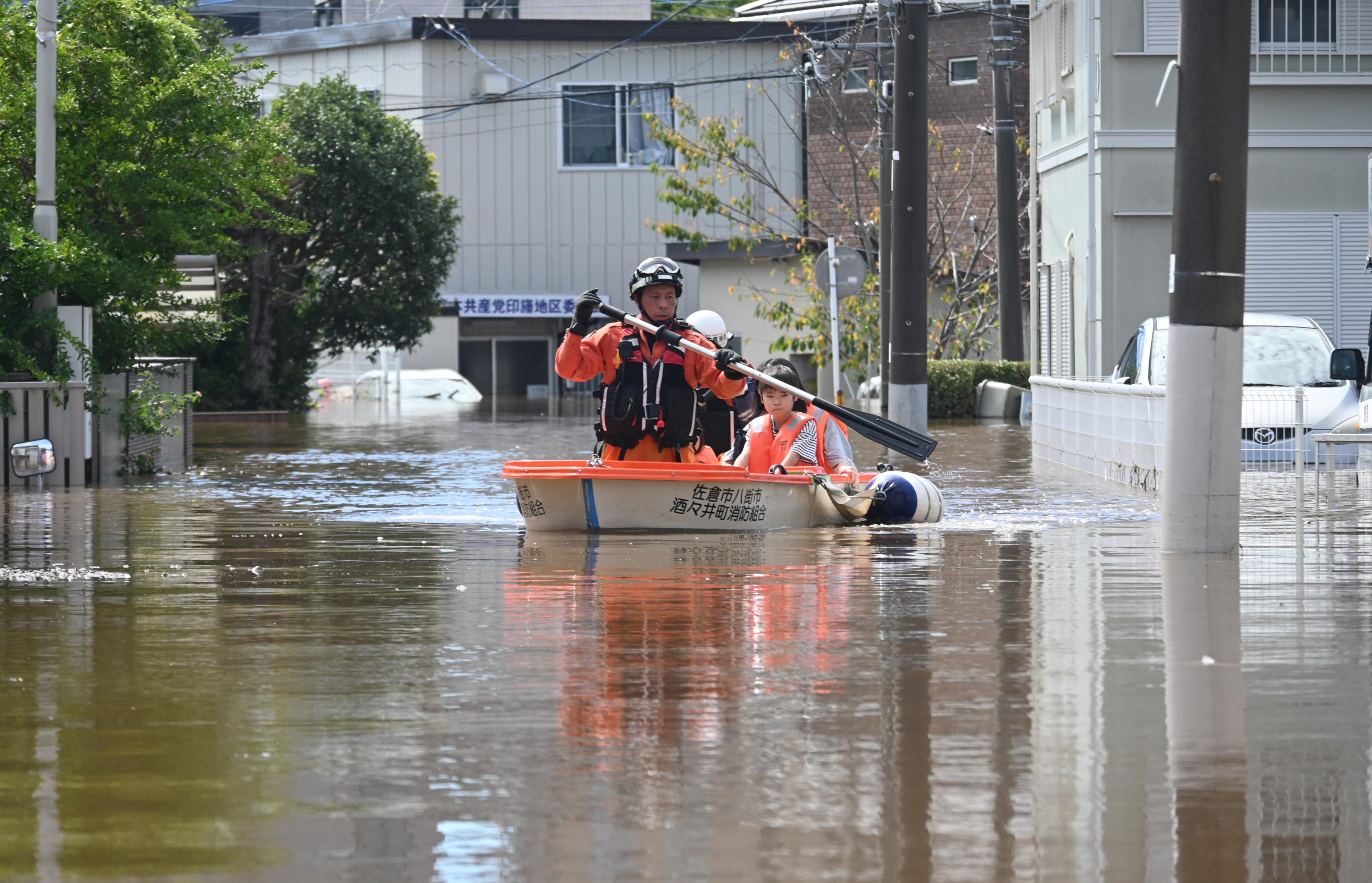 Firefighters row a boat on a flooded street to rescue a parent and a child from an isolated apartment after the previous day’s heavy rain from Typhoon Dujuan in Sakura City, Chiba Prefecture, Japan, on September 22, 2026. Typhoon Dujuan, the season’s 25th typhoon, passed over the Izu Islands and the Pacific coast of the Kanto Region on the 21st, bringing record rainfall and landslides. ( The Yomiuri Shimbun )