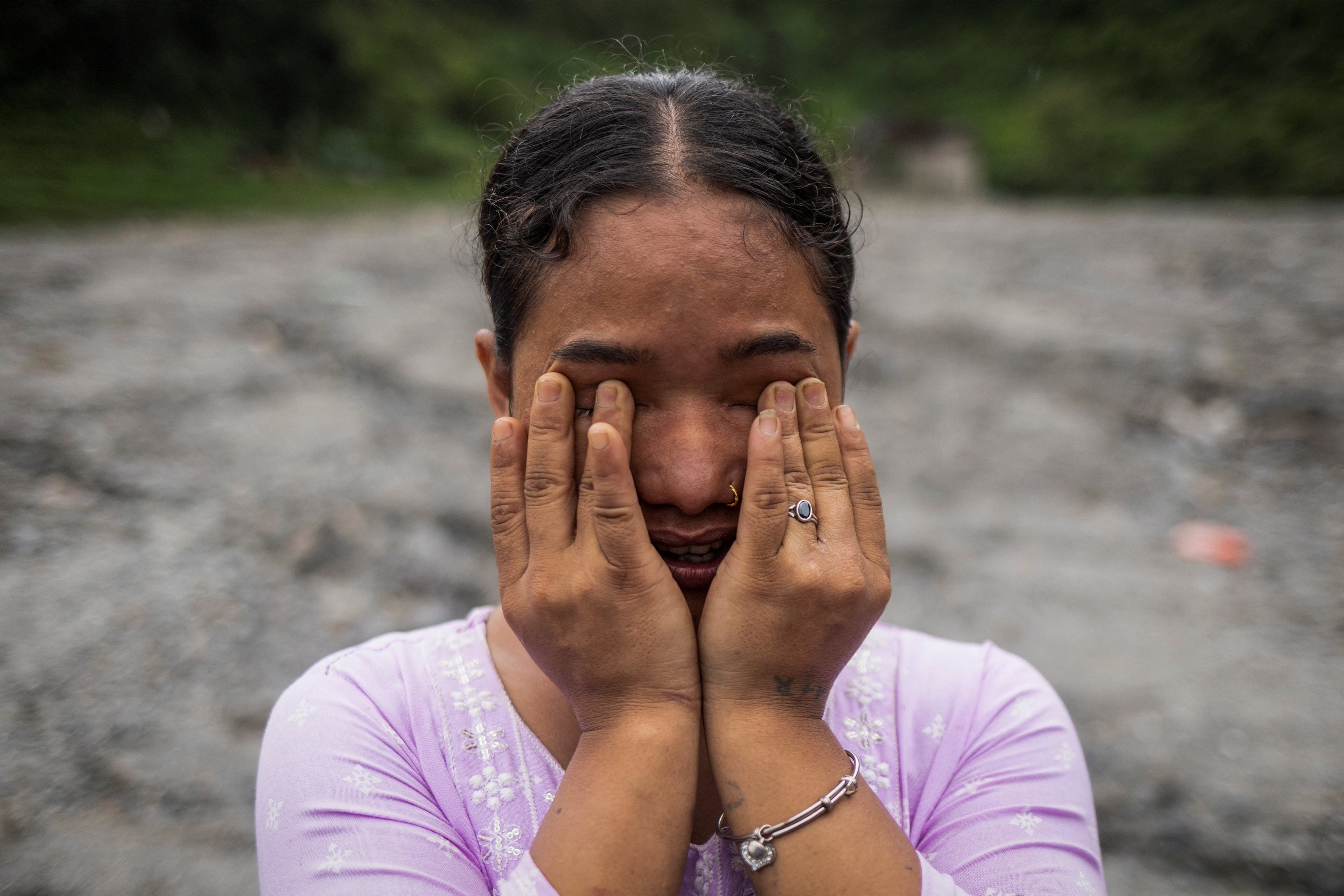 Anusa Thapa Magar, 23, displaced by recent flash floods and mudslides, cries as she poses for a photograph on the sludge that buried her home in Betrawati, Nuwakot district, Nepal, September 9, 2026. Magar returned from working in the Maldives after hearing about the disaster and fears her grandmother may still be buried beneath the family home. "If my house is buried underneath, that means my Aama is still here underneath too, right?" she said. REUTERS/Adnan Abidi             SEARCH "SIU ABIDI NEPAL SURVIVORS" FOR THIS STORY. SEARCH "WIDER IMAGE" FOR ALL STORIES.