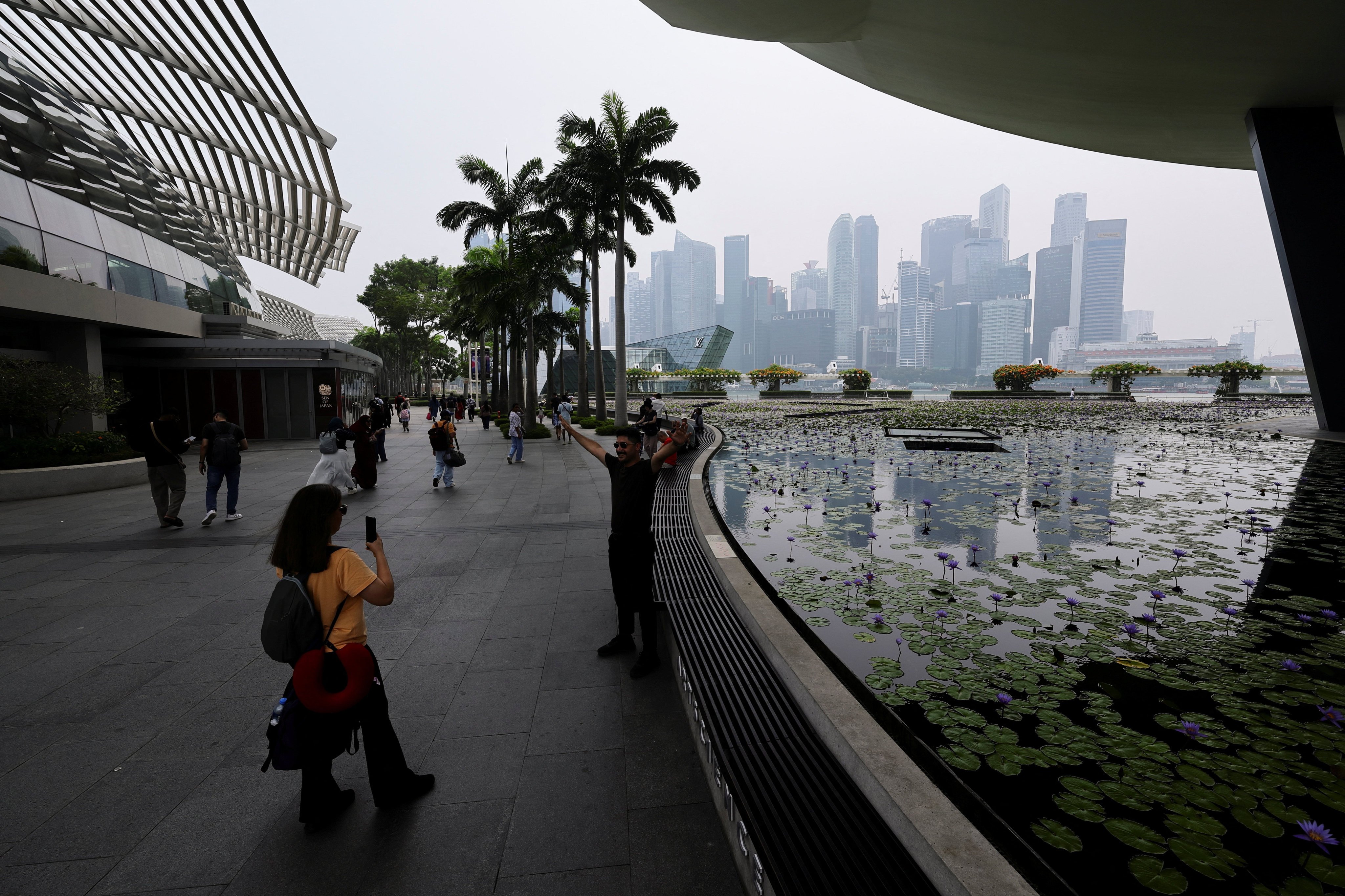 People take pictures with the city skyline of Singapore on September 14. The Iran conflict has accelerated Gulf businesses’ use of Asian financial hubs, insiders say. Photo: Reuters