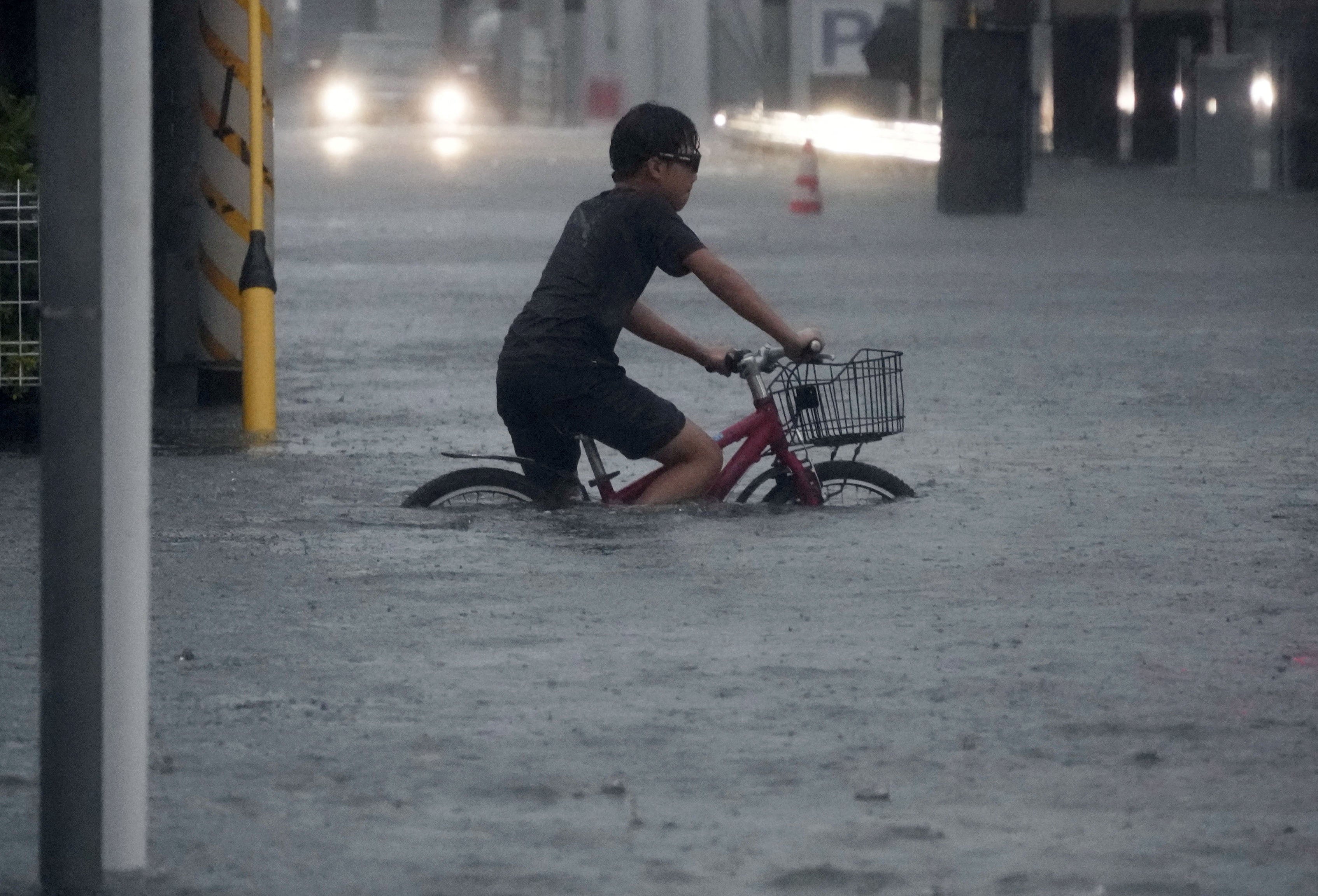 A boy cycles through a flooded street in Ichikawa, Chiba prefecture, Japan, on Monday. Photo: Kyodo via Reuters