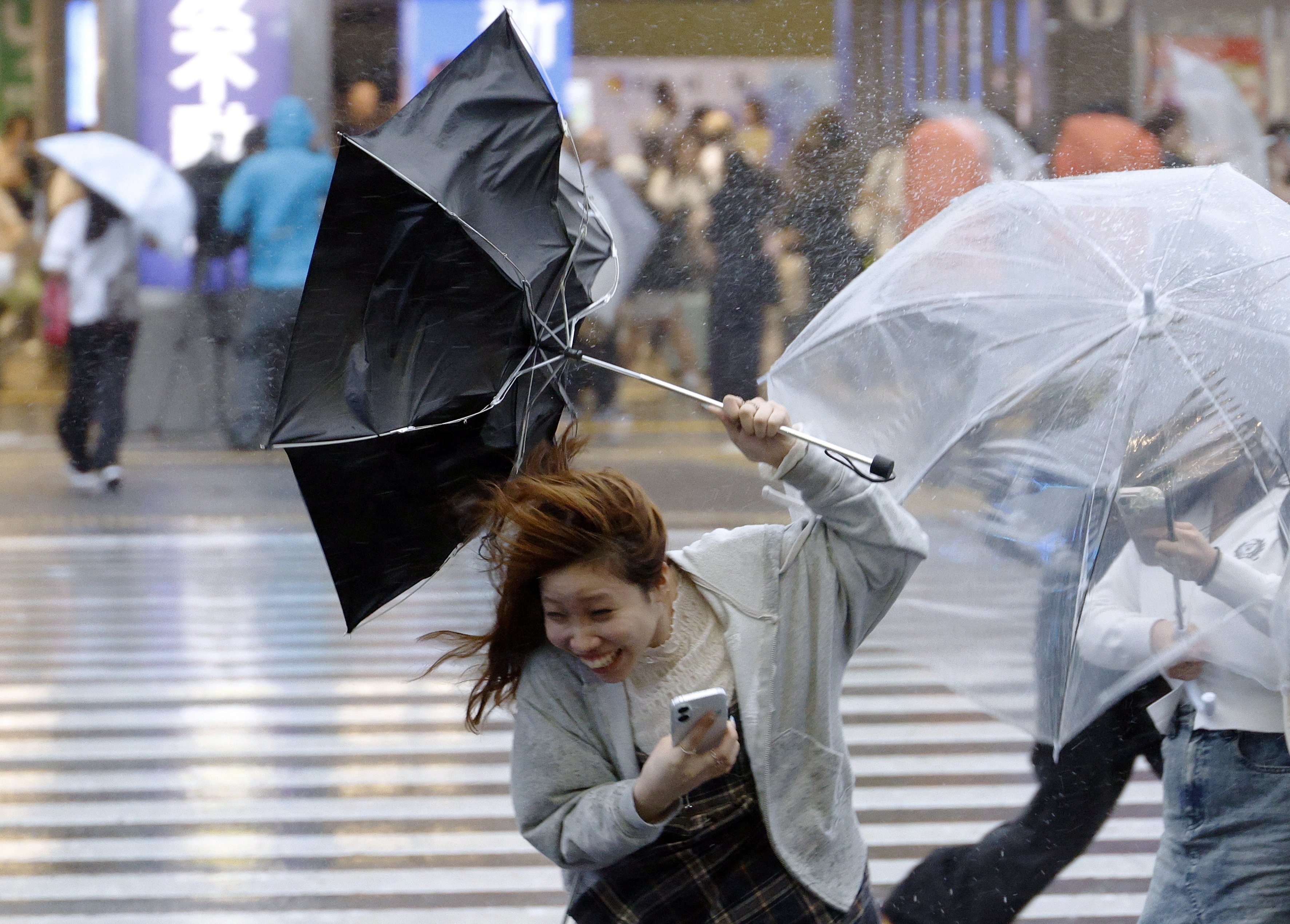 A woman struggles to handle her umbrella under heavy rain and wind triggered by Typhoon Dujuan near Shinjuku station in Tokyo, Japan, on Monday. Photo: EPA