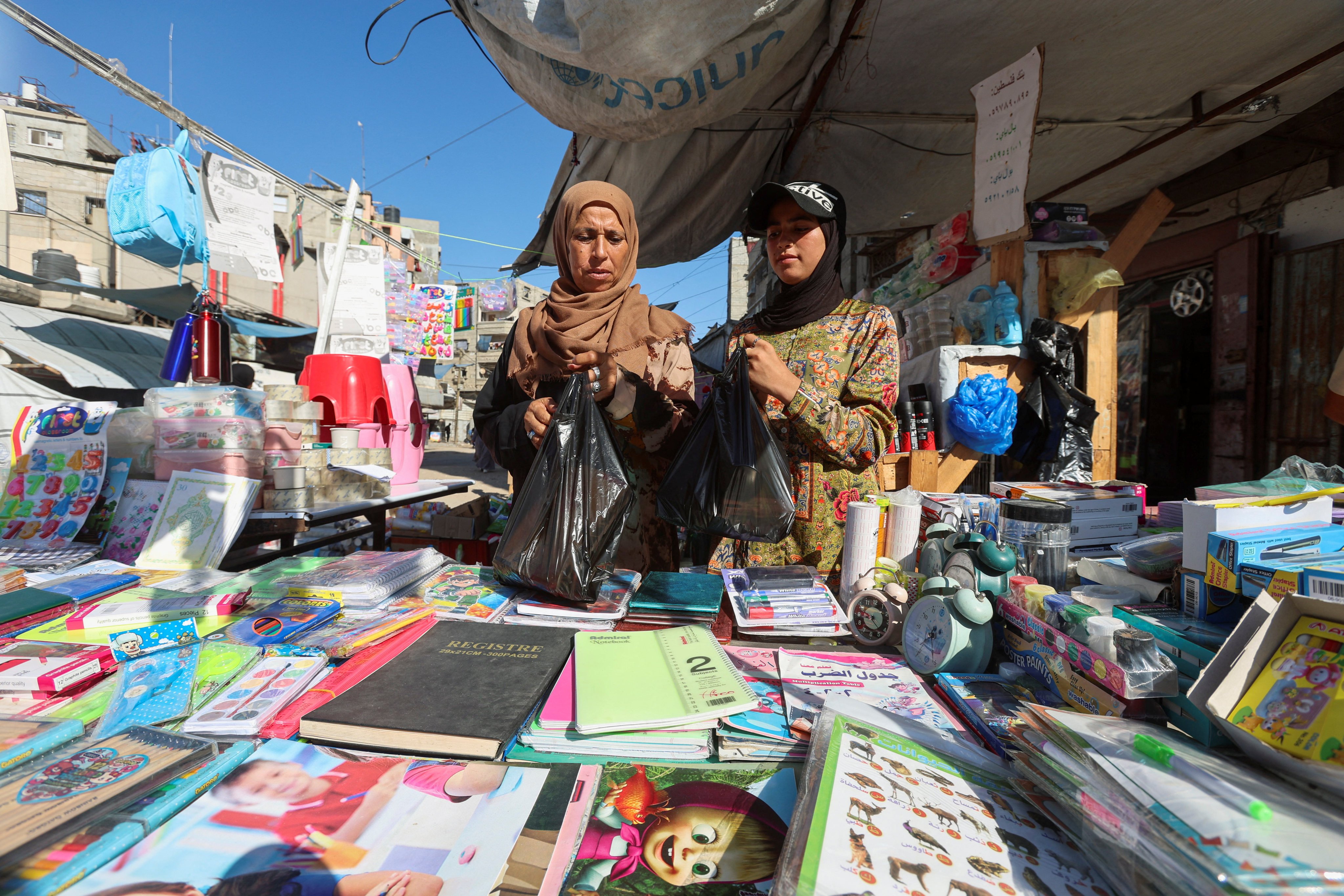 Displaced Palestinian student Samar Abu Salmi, 15, and her mother Ghalia Abu Salmi look at stationery at a stall in Khan Younis in the southern Gaza Strip. Photo: Reuters