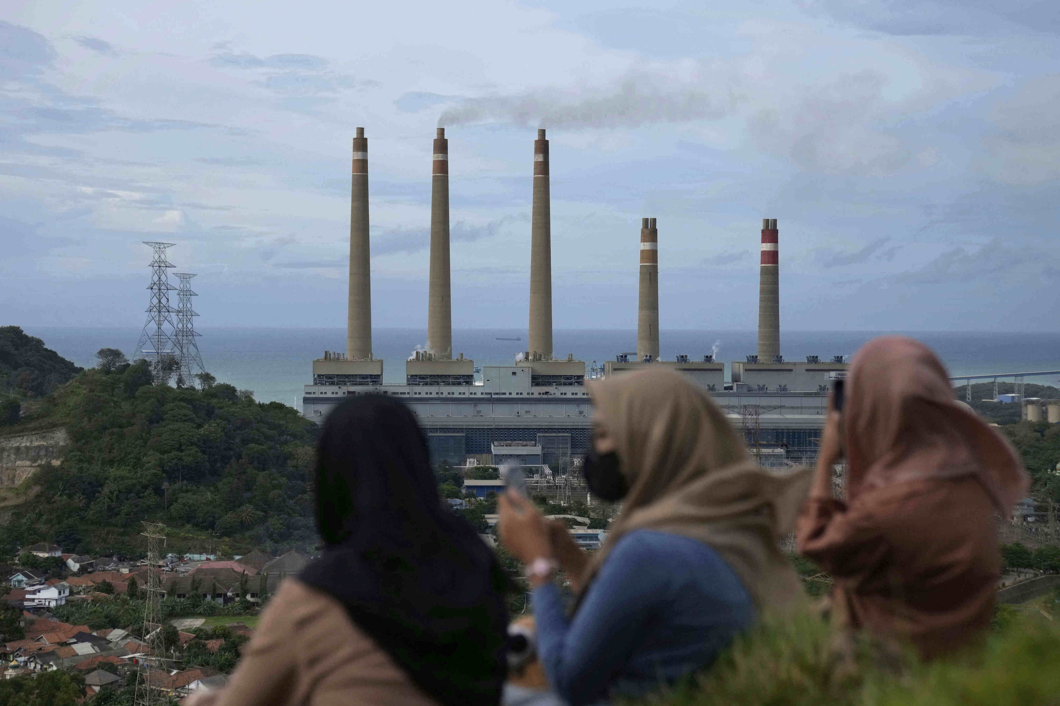 Women sit on a hill overlooking a coal power plant in Indonesia. The country is a hotspot for Chinese energy investment. Photo: AP