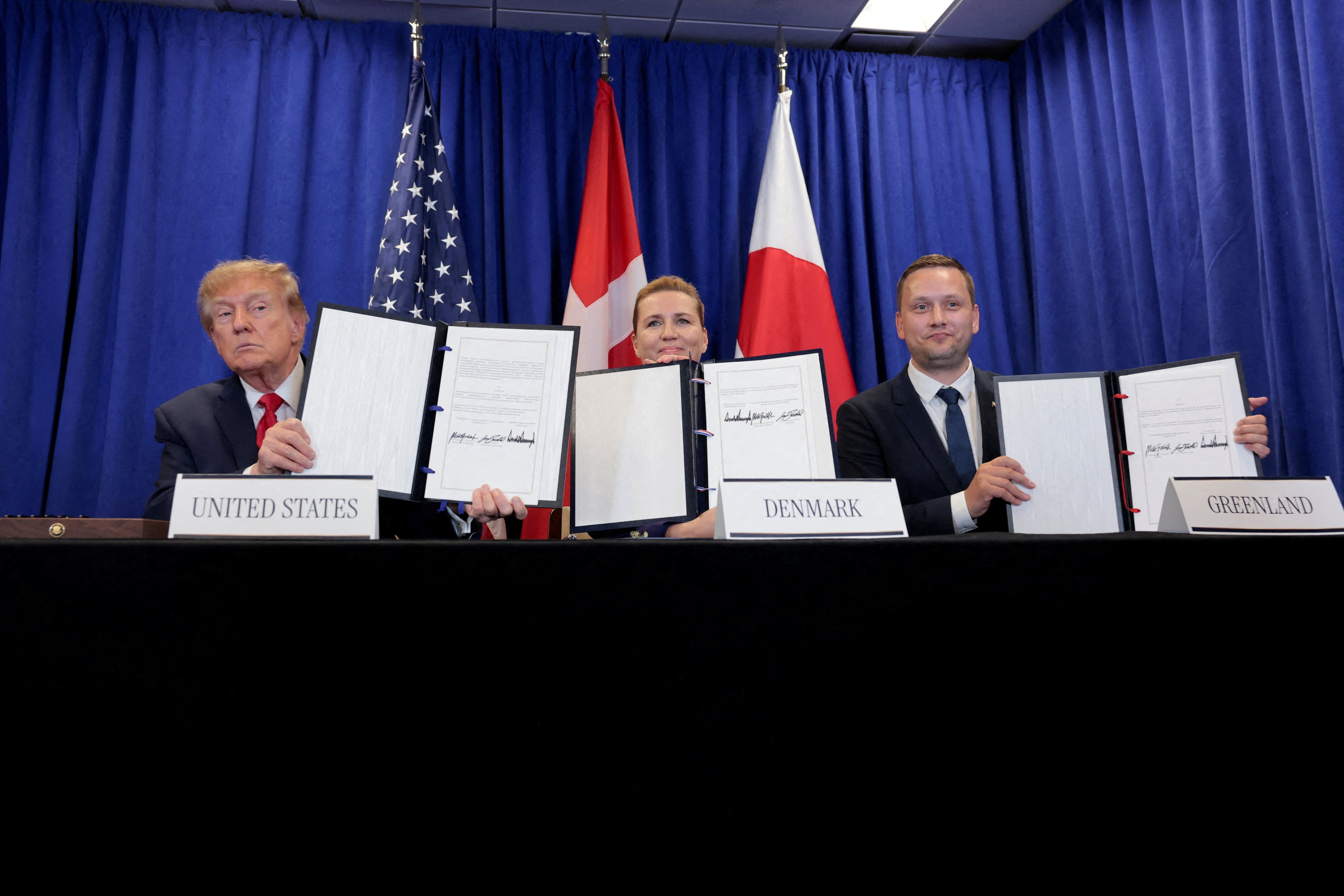 The leaders hold up the signed documents. Photo: Reuters