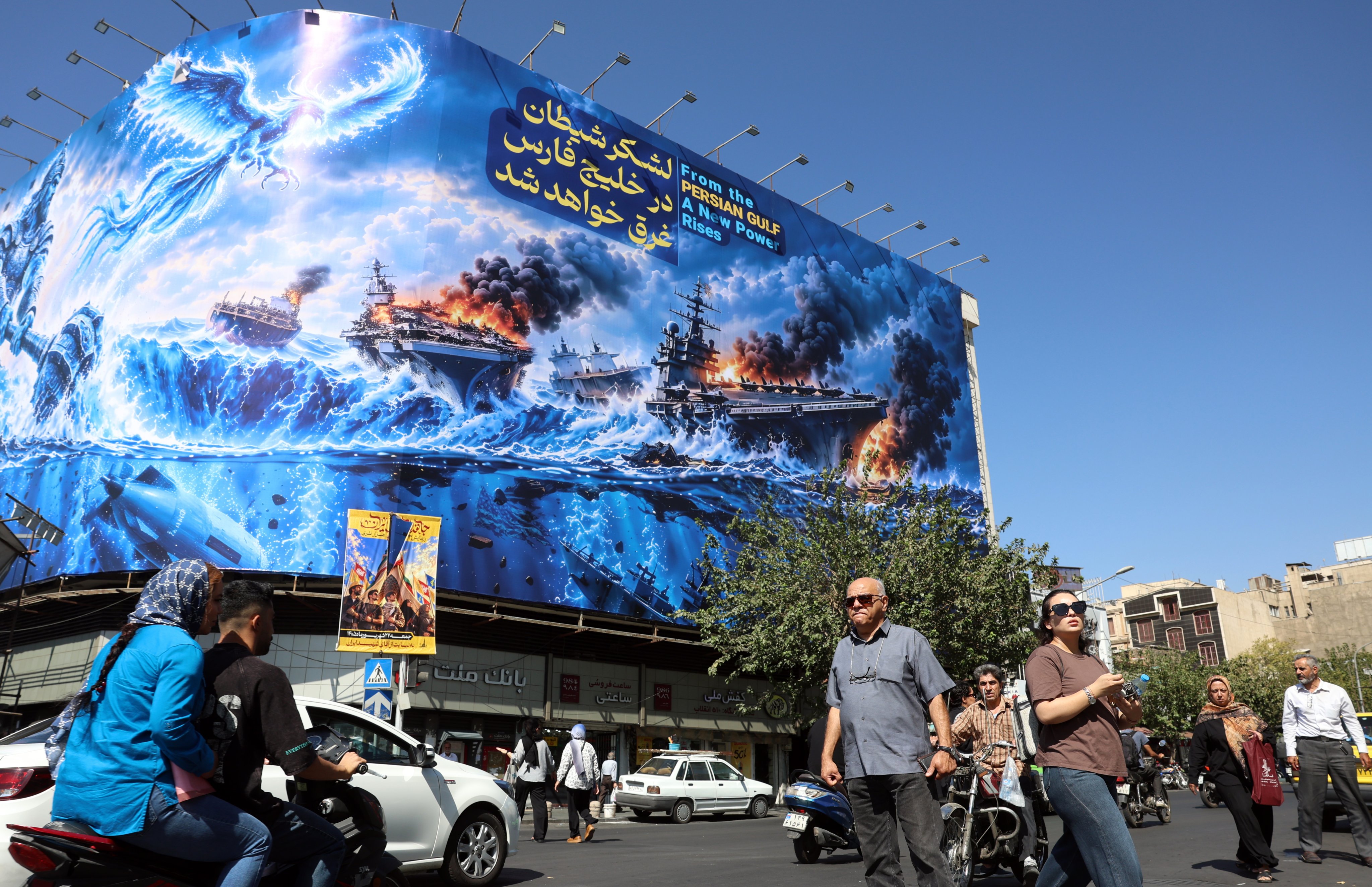 Iranians walk next to an anti-US billboard carrying a sentence in Persian that reads “The devil army will be drowned in the Persian Gulf” in Tehran on Monday. Photo: EPA