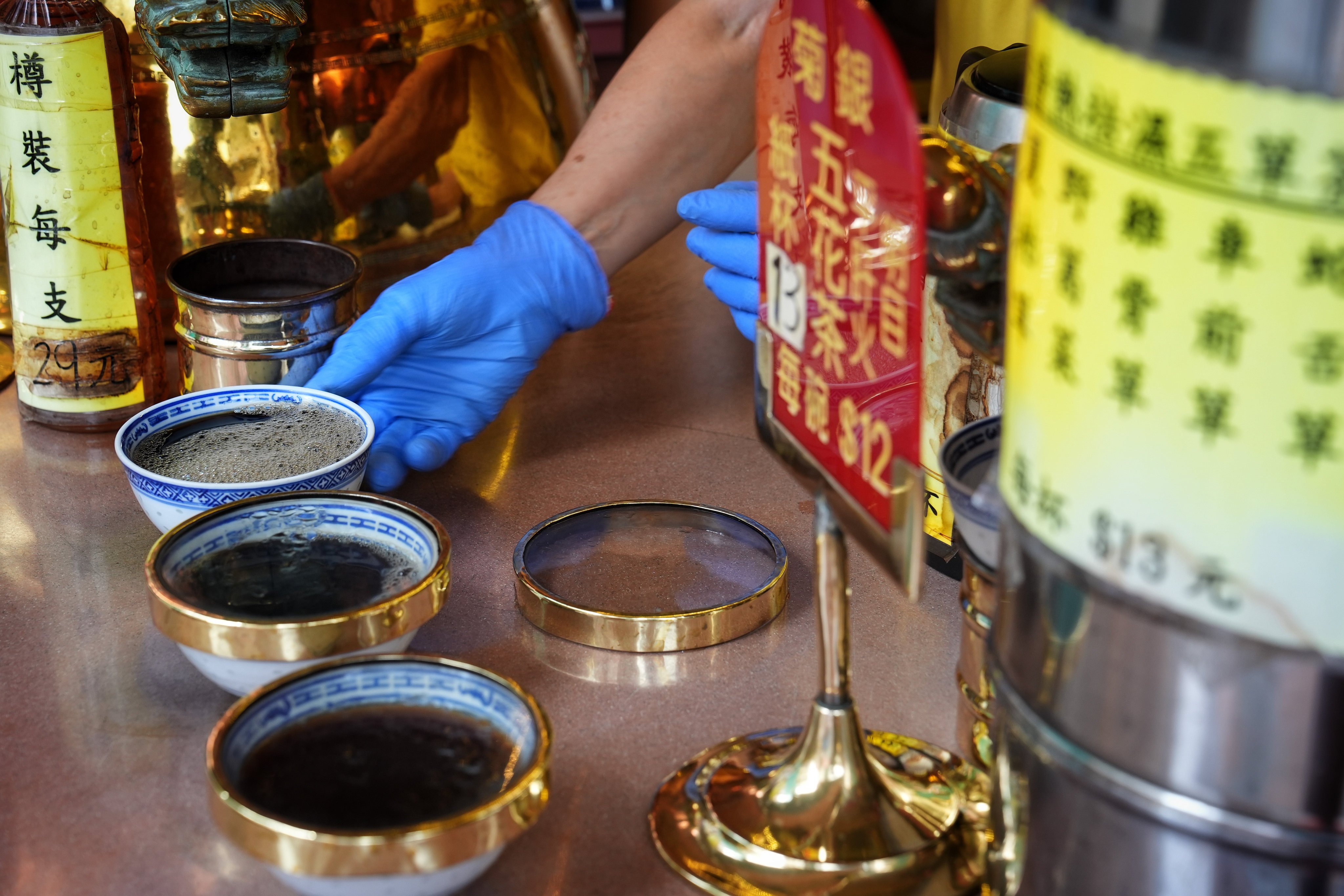 A staff member fills bowls with herbal tea known as leung cha (“cooling tea”) from a giant copper pot at Pak Po Tong on Temple Street in Hong Kong. Photo: Elson Li
