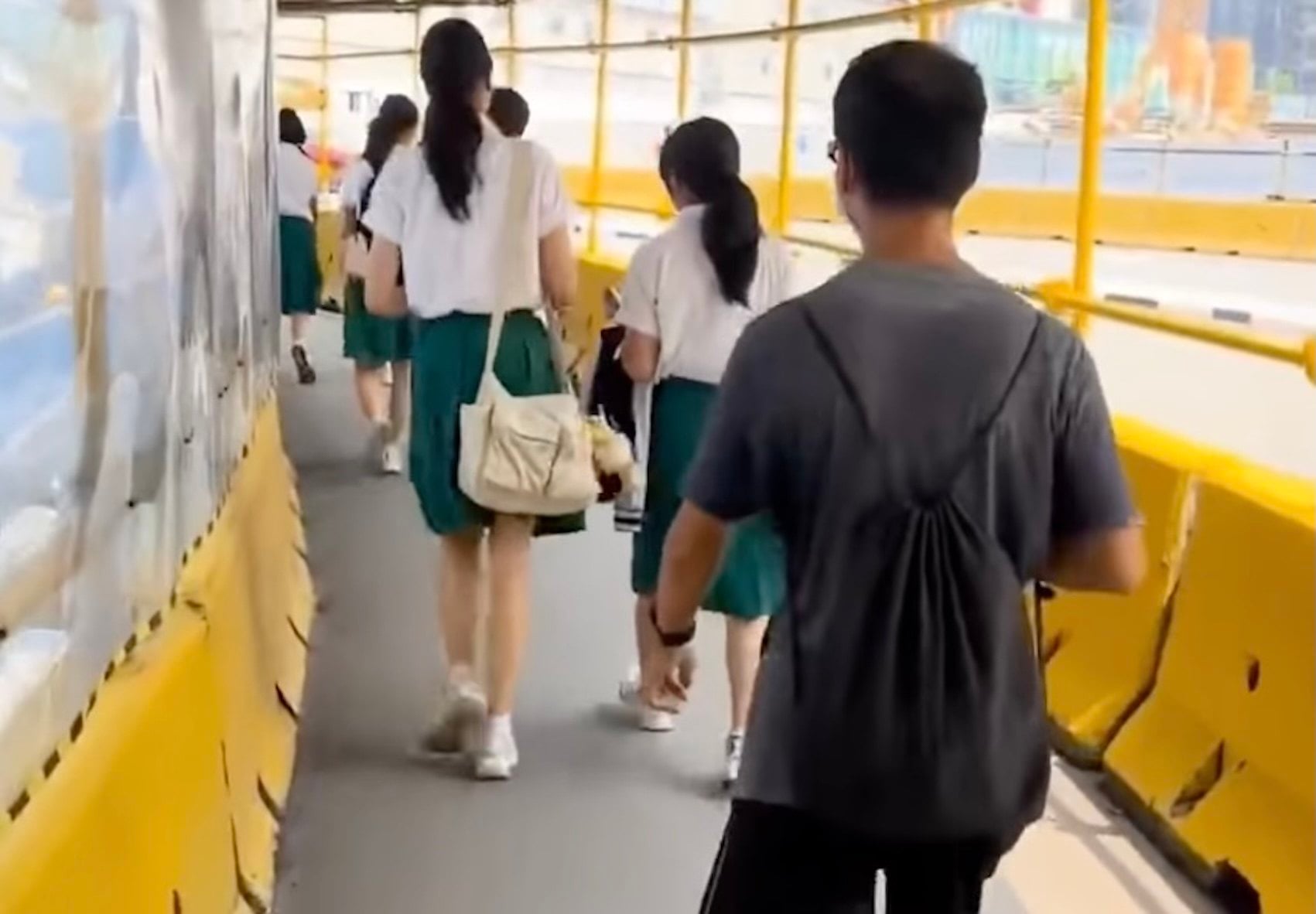 A man wearing black-rimmed glasses and a face mask is seen walking behind two female students in Singapore. Photo: Reddit/Bblackjack160