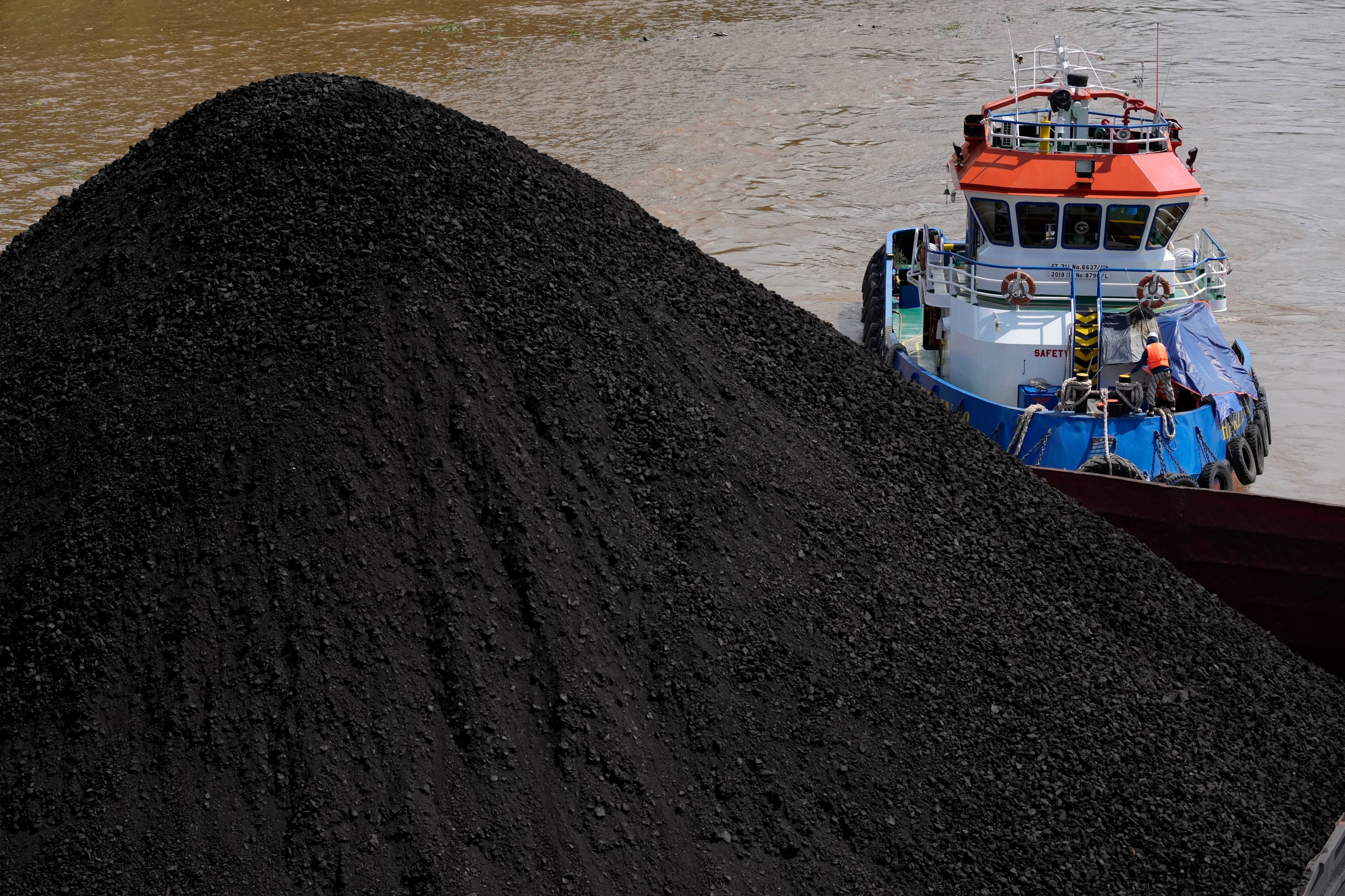 A tug boat pushes a barge carrying coal on Mahakam river in Samarinda, East Kalimantan, Indonesia. Photo: AP