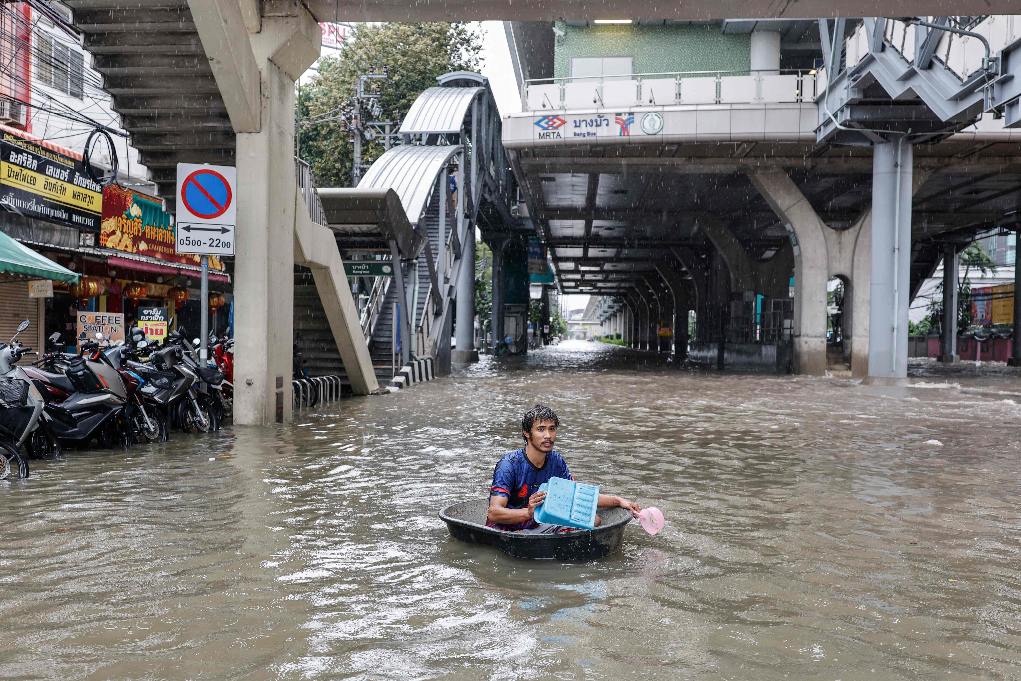 A man uses a large plastic tube to wade through floodwaters in the Bang Bua district of Bangkok on Saturday. Photo: AFP