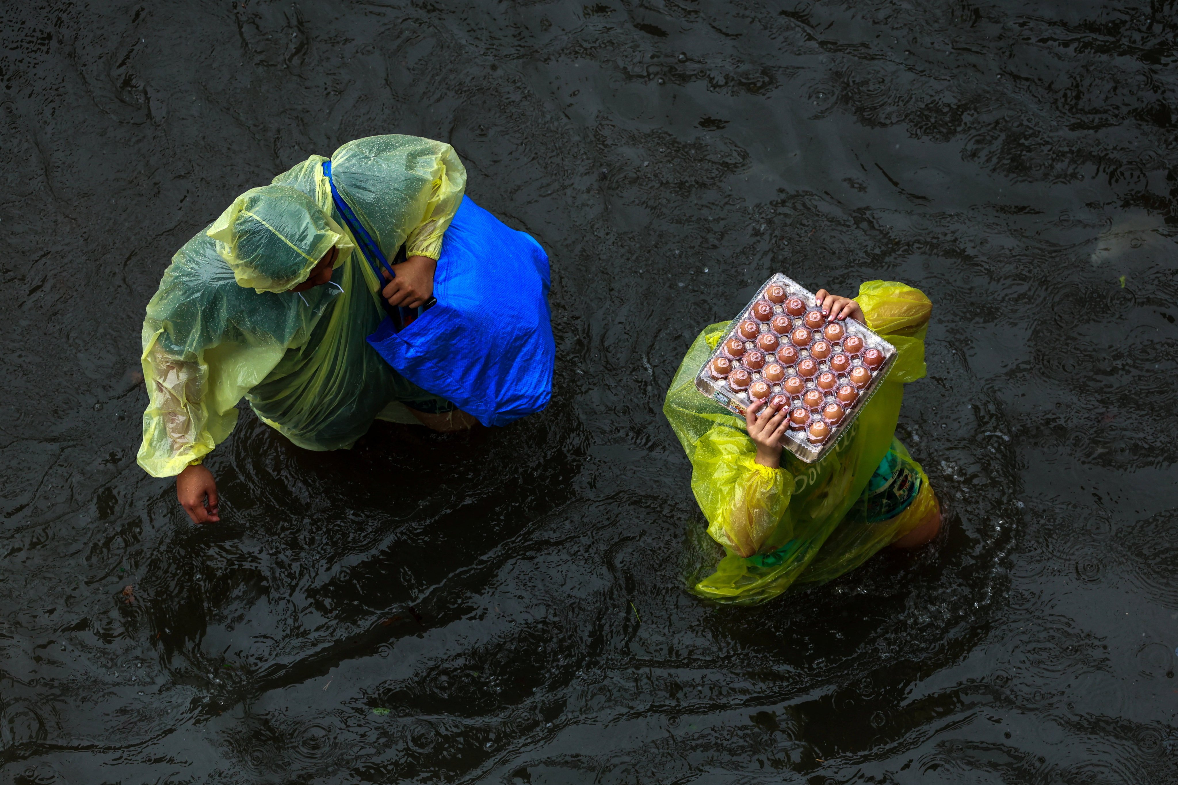 People carry food during heavy rain in Bangkok on Saturday. Photo: Reuters