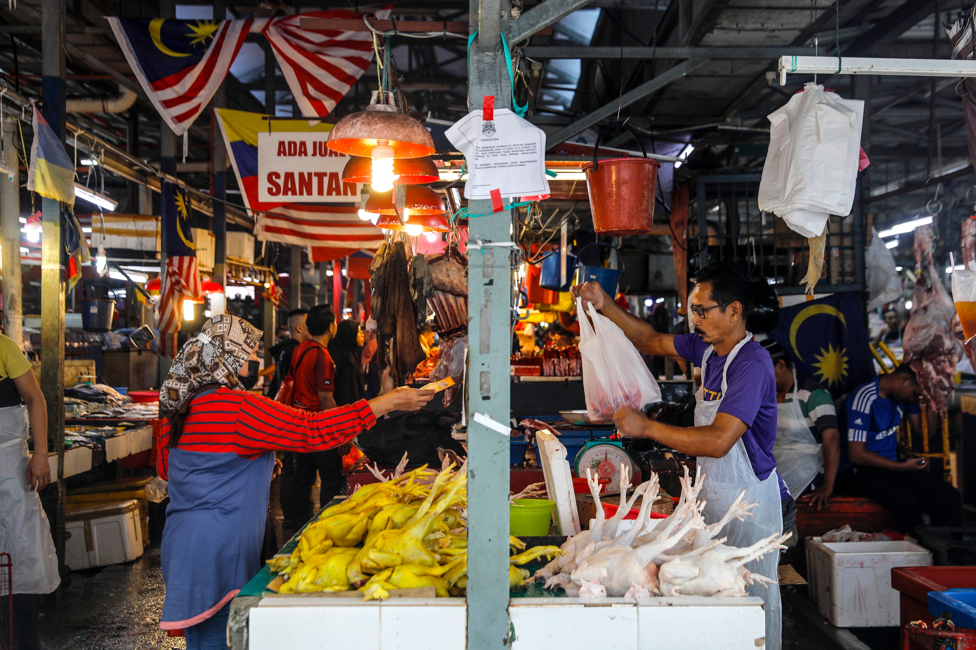 A customer buys a chicken from a vendor at a wet market in Kuala Lumpur. Photo: EPA-EFE