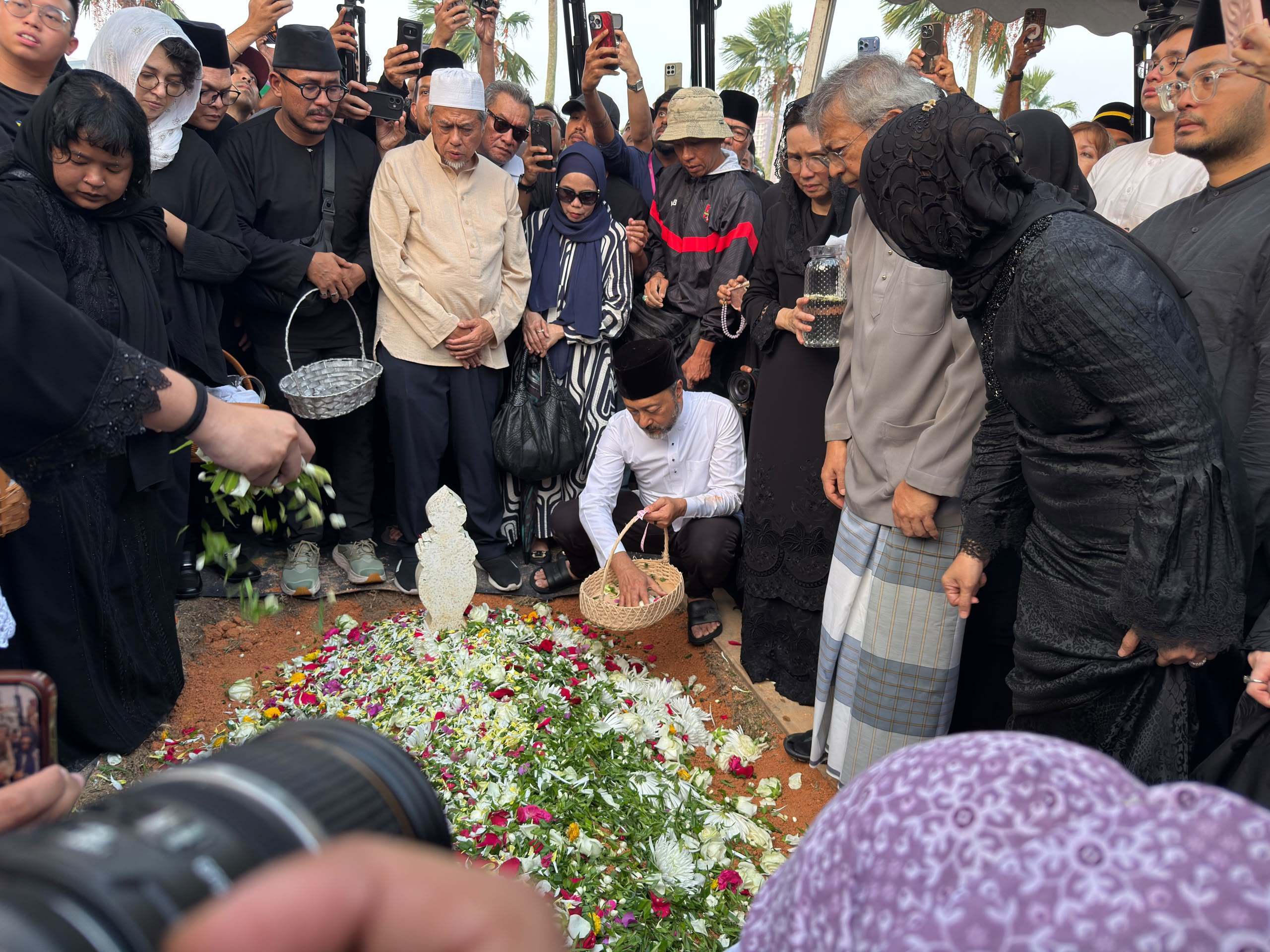 Mukhriz Mahathir (in white) scatters flower petals over the grave of his mother, Siti Hasmah Mohamad Ali, at the National Heroes’ Mausoleum in Putrajaya, Malaysia, on Monday. Photo: Iman Muttaqin Yusof