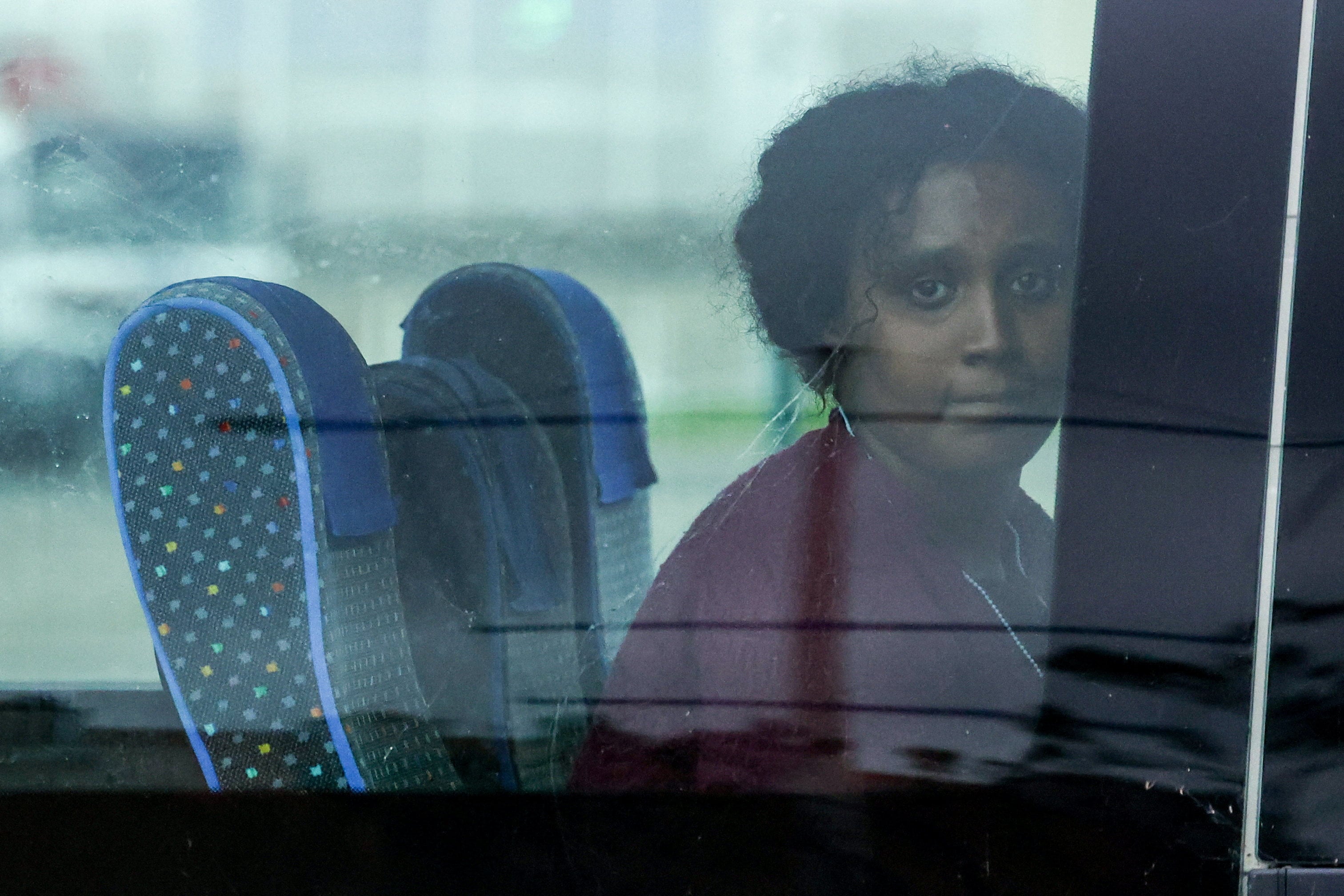 A migrant sits in a bus as she leaves the rescue area of the French port of Calais on Monday. Three other migrants, including a child aged 10, died while attempting to cross the sea to Britain. Photo: Reuters
