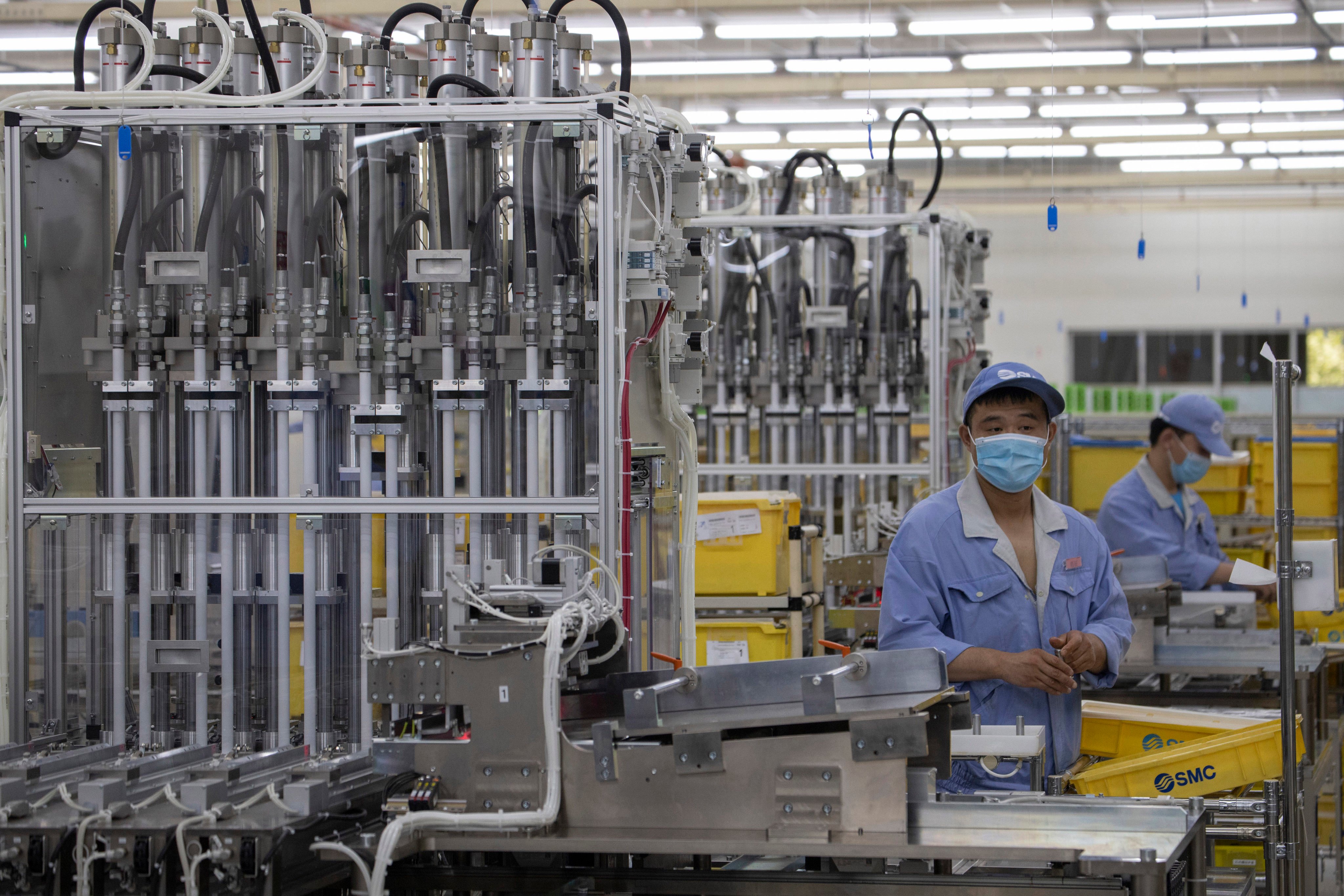Workers at SMC, a Japanese pneumatic engineering company, assemble products at a factory in Beijing, May 13, 2020. Photo: AP