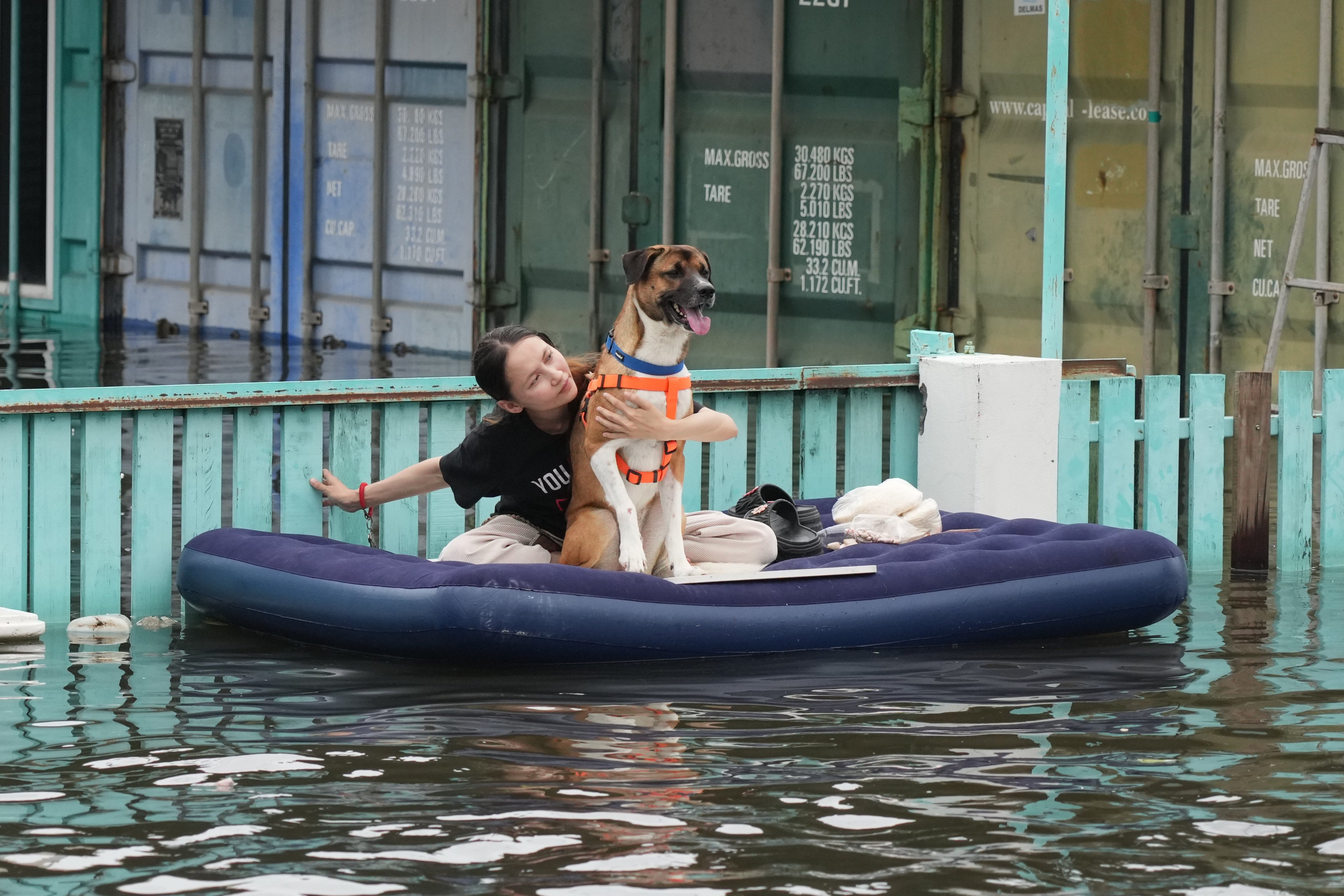 A woman with her dog rides a rubber raft through a flooded street in Bangkok on Monday. Photo: AP