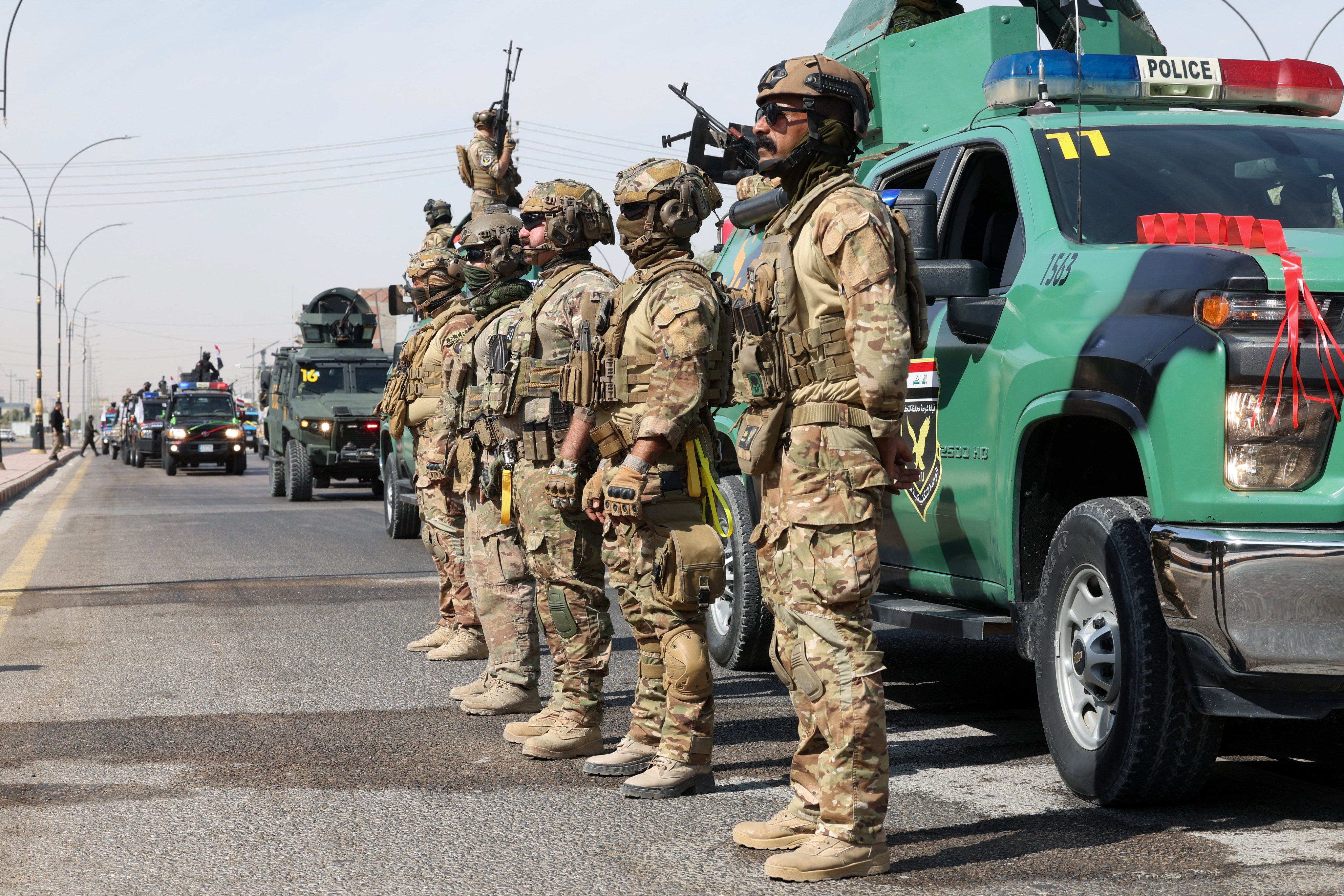 Members of the Iraqi security forces stand next to a convoy moving through the city as they celebrate the withdrawal of US-led coalition forces from Iraq in Najaf, Iraq, on Wednesday. Photo: Reuters