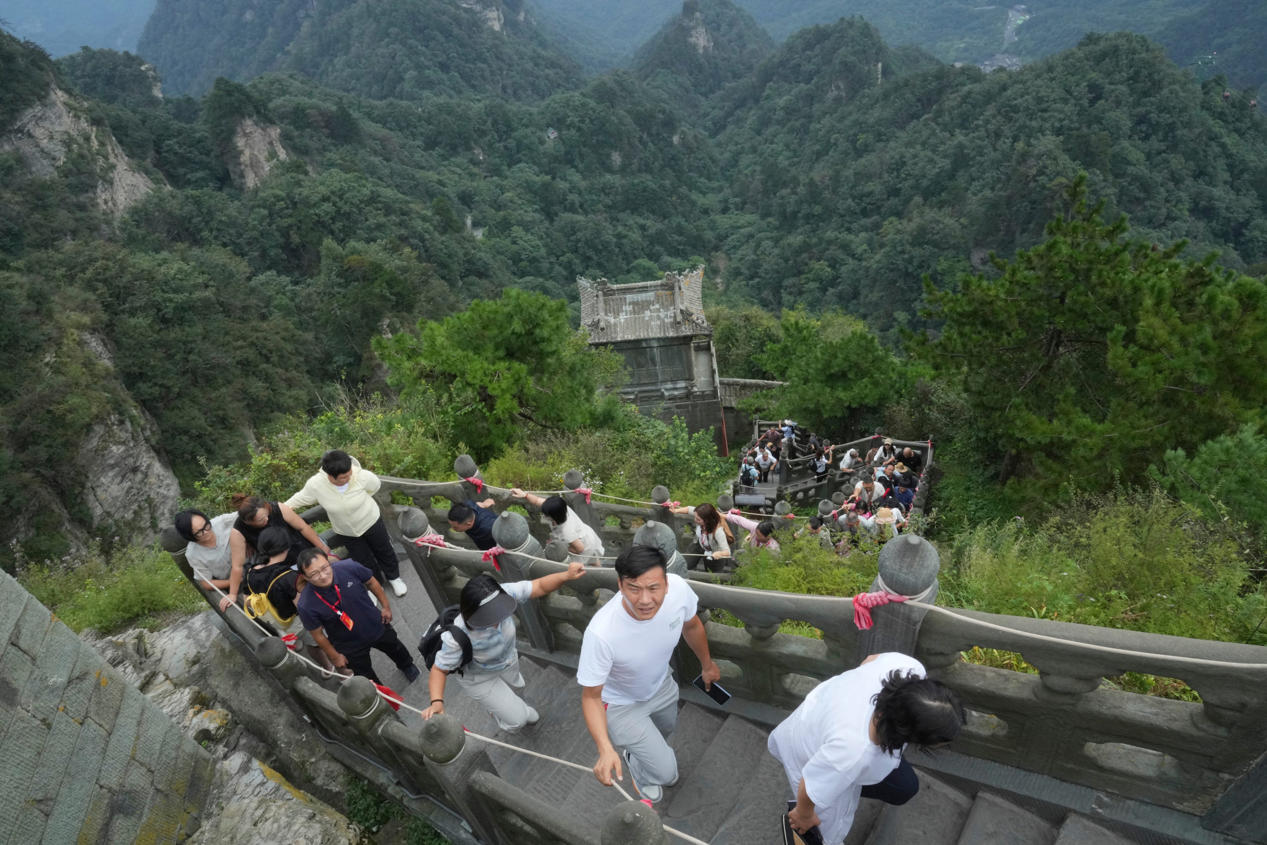 Visitors climb up the stairs near the Golden Hall in Wudang Mountains in central China’s Hubei Province on  Sept. 3, 2026. (AP Photo/Achmad Ibrahim)
