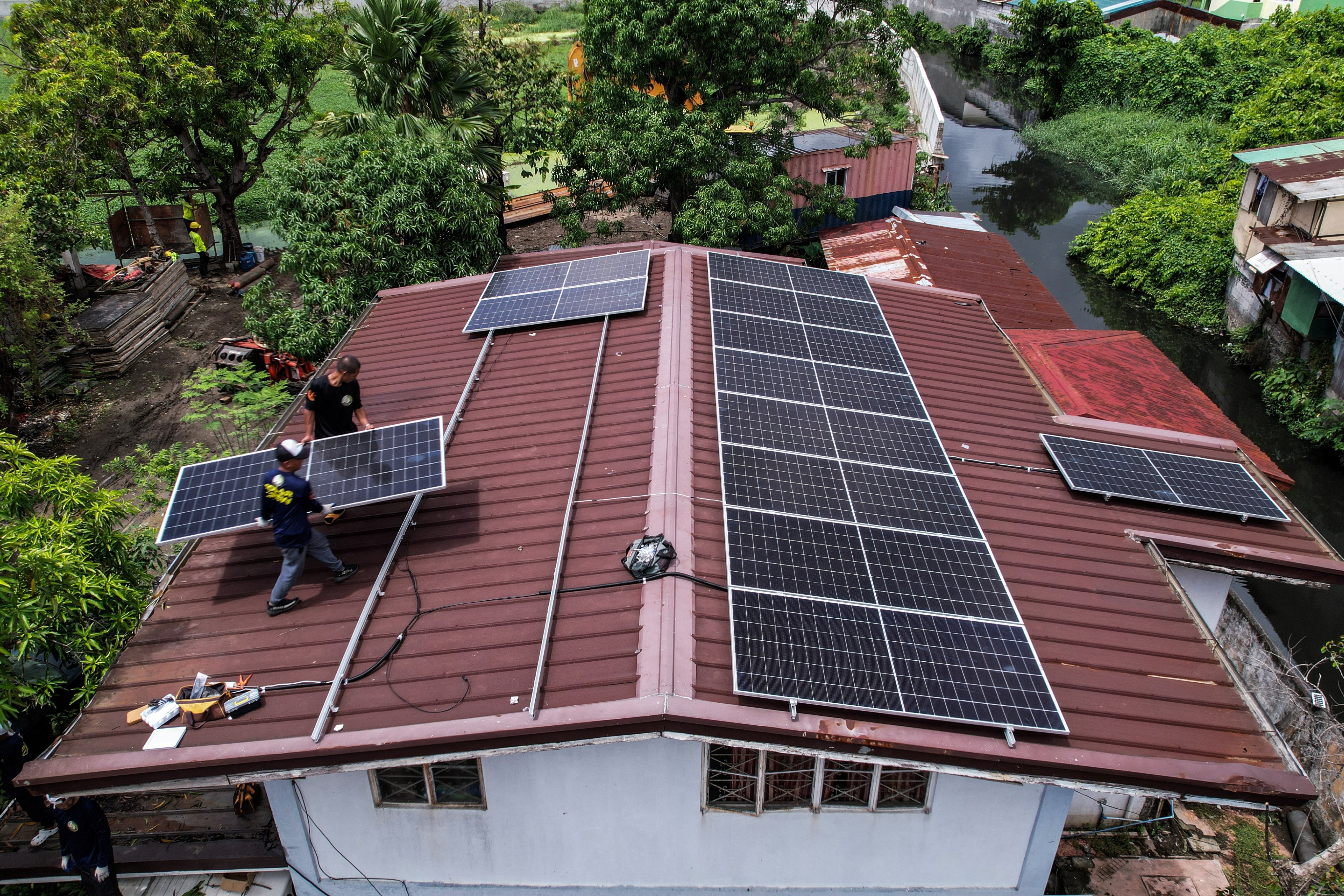 Workers installing solar panels on the roof of a house in Kawit, the Philippines, in June. Photo: Reuters