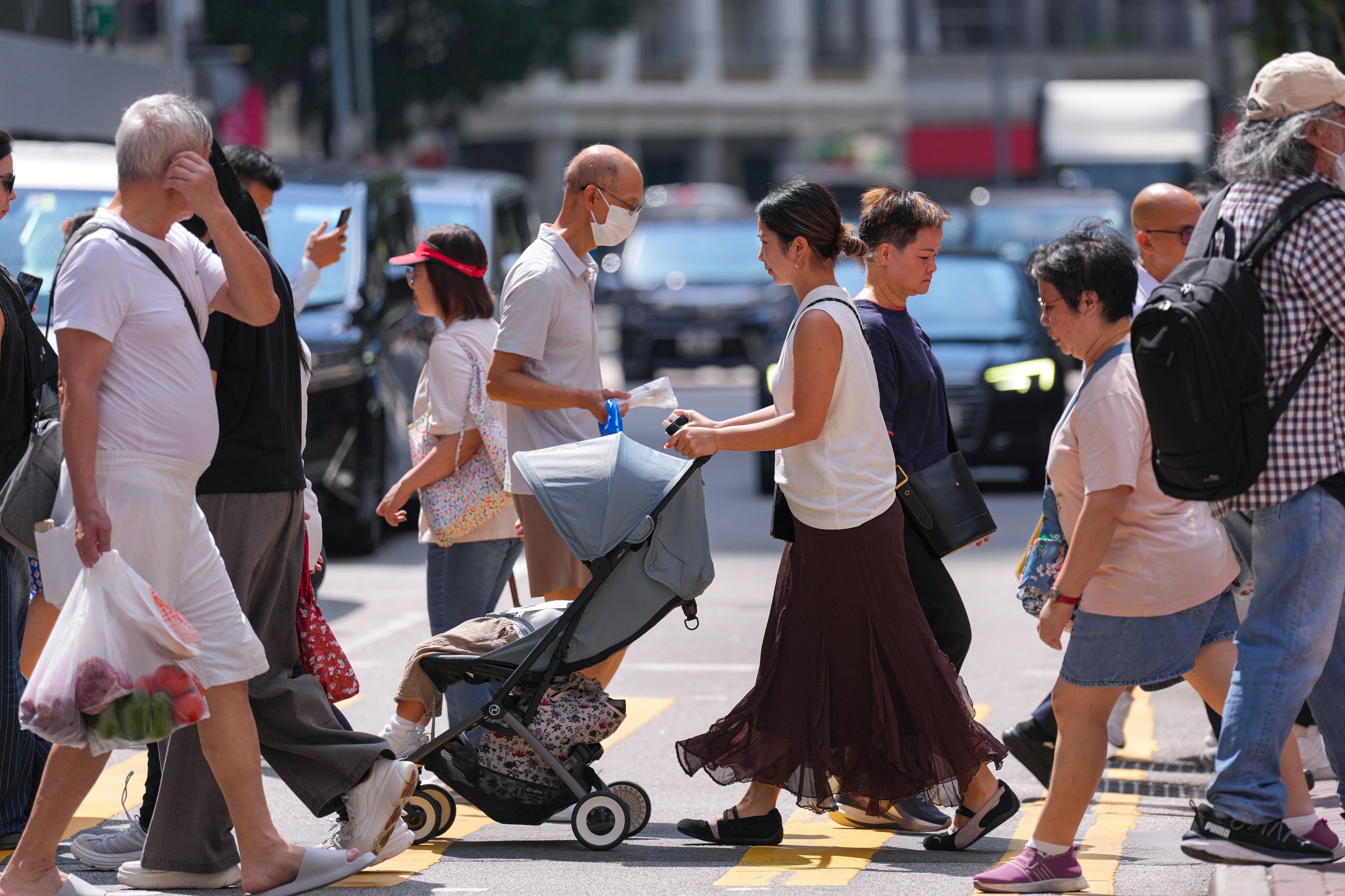 A toddler sits in a stroller as pedestrians navigate a street in Wan Chai on September 16. In the latest policy address, the government has rolled out 11 new initiatives to encourage residents to have children. Photo: Karma Lo