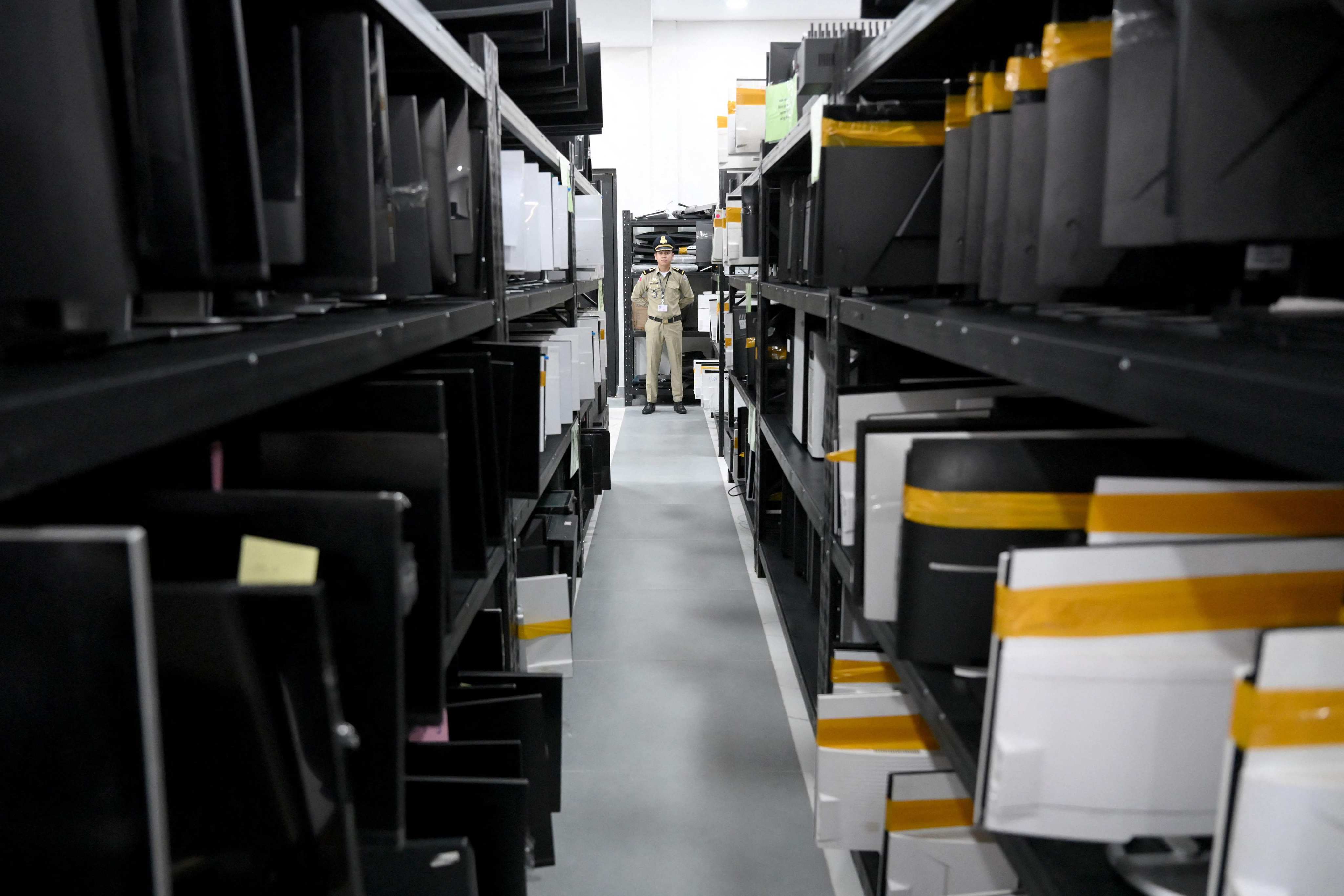 A police officer stands guards near seized equipment confiscated from online scam operation centres at the Commissariat of Phnom Penh Municipal Police in Phnom Penh on September 22. Photo: AFP