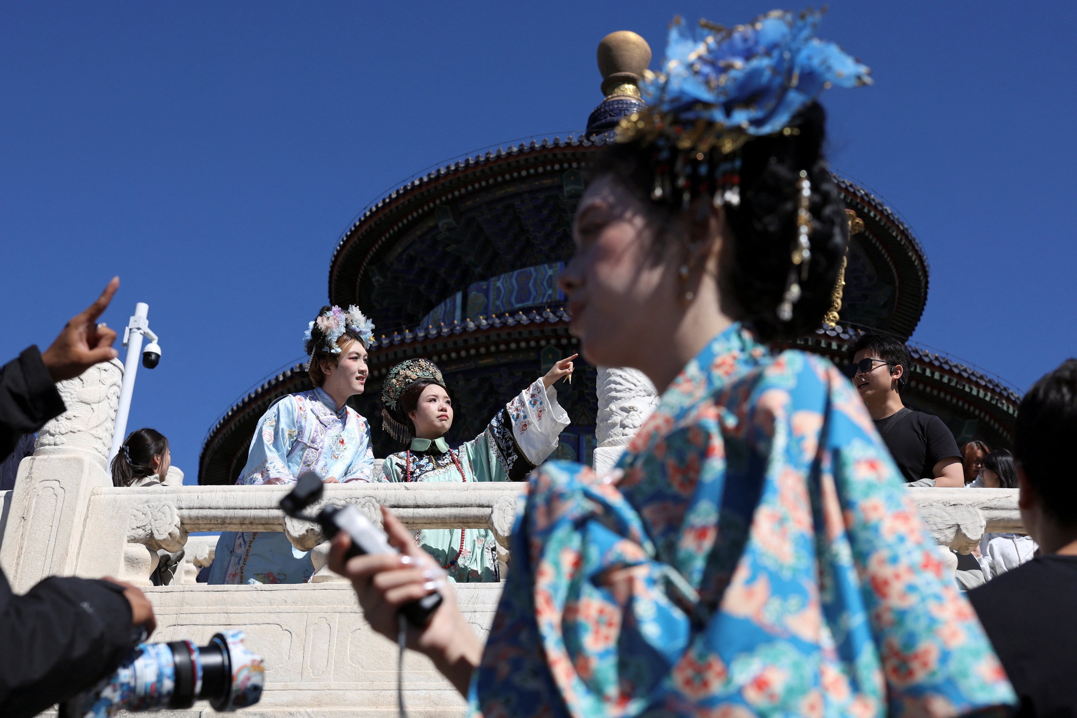 A photographer directs visitors dressed in traditional costumes to pose for pictures at Temple of Heaven, also known as Tiantan Park, on National Day, the first day of China's Golden Week holiday, in Beijing, China, October 1, 2026. REUTERS/Florence Lo