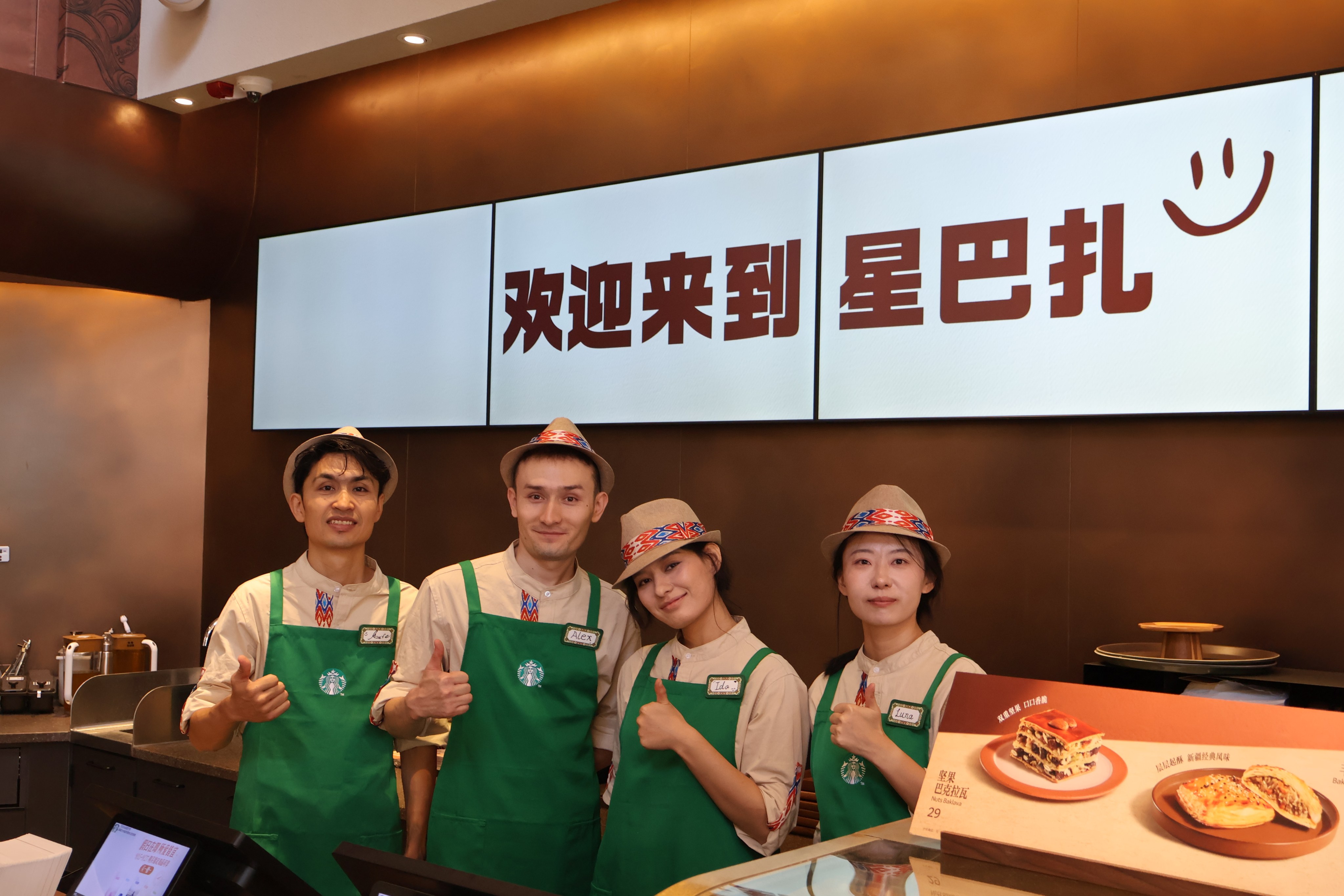 Employees pose at a Starbucks store in Urumqi, the capital of the Xinjiang Uygur autonomous region, on September 29. International coffee chain giant Starbucks has opened two stores in Xinjiang, marking its debut in the region and the latest expansion in China, its second-largest market after the United States. Photo: Xinhua