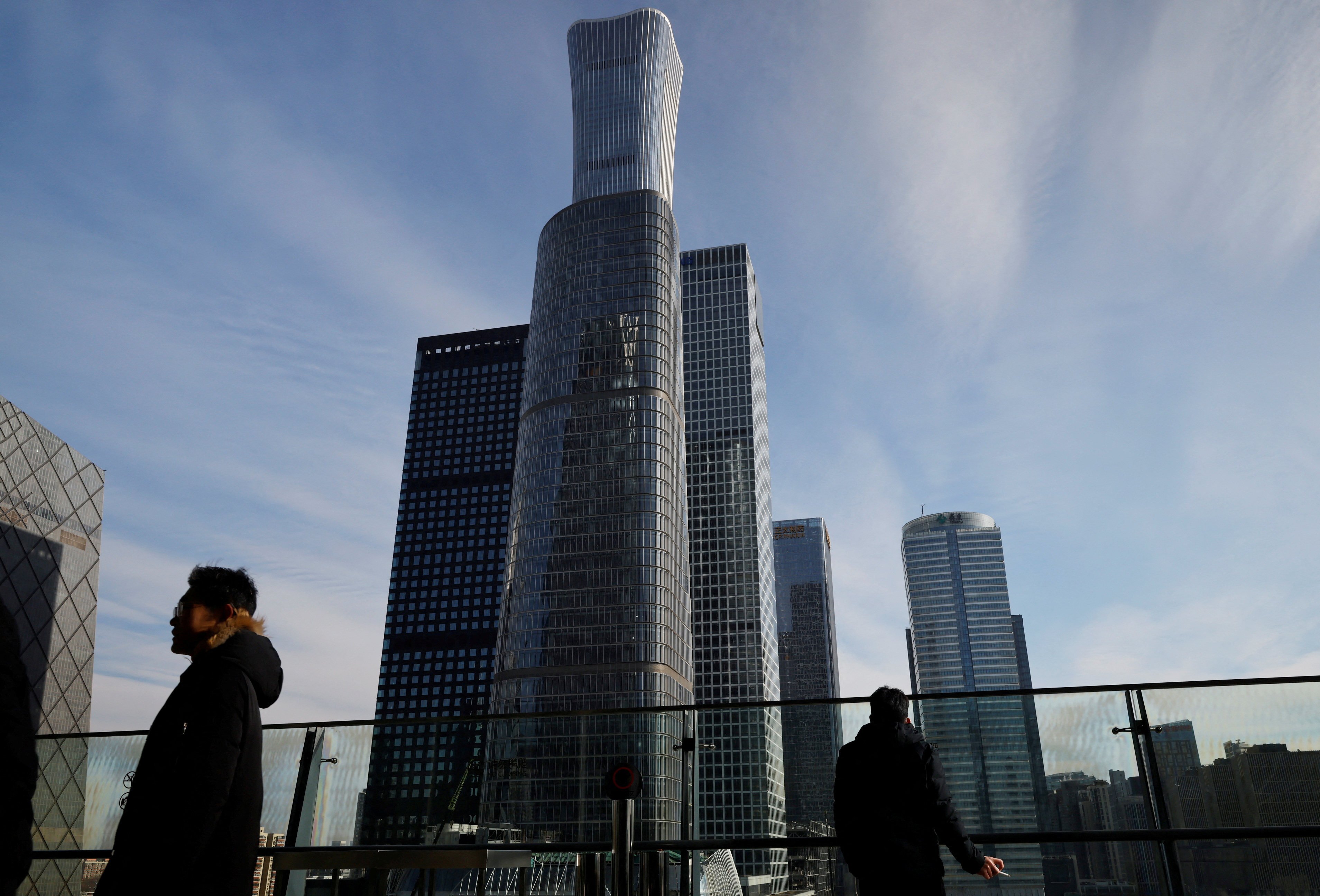 Men stand on a balcony overlooking the central business district in Beijing. Photo: Reuters