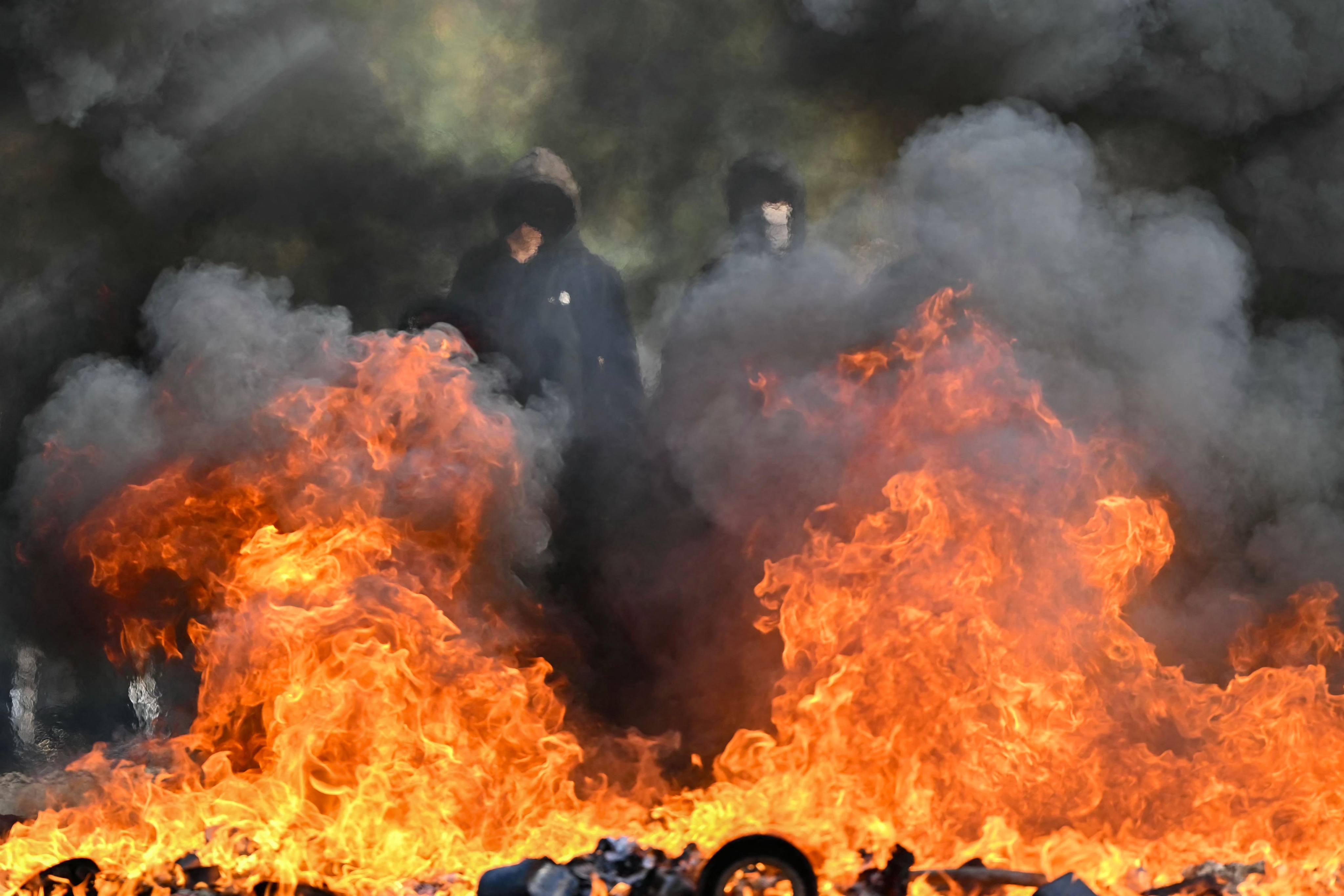 Protesting high schoolers gather behind a burning barrier in Aubervilliers, near Paris on Thursday. Photo: AFP