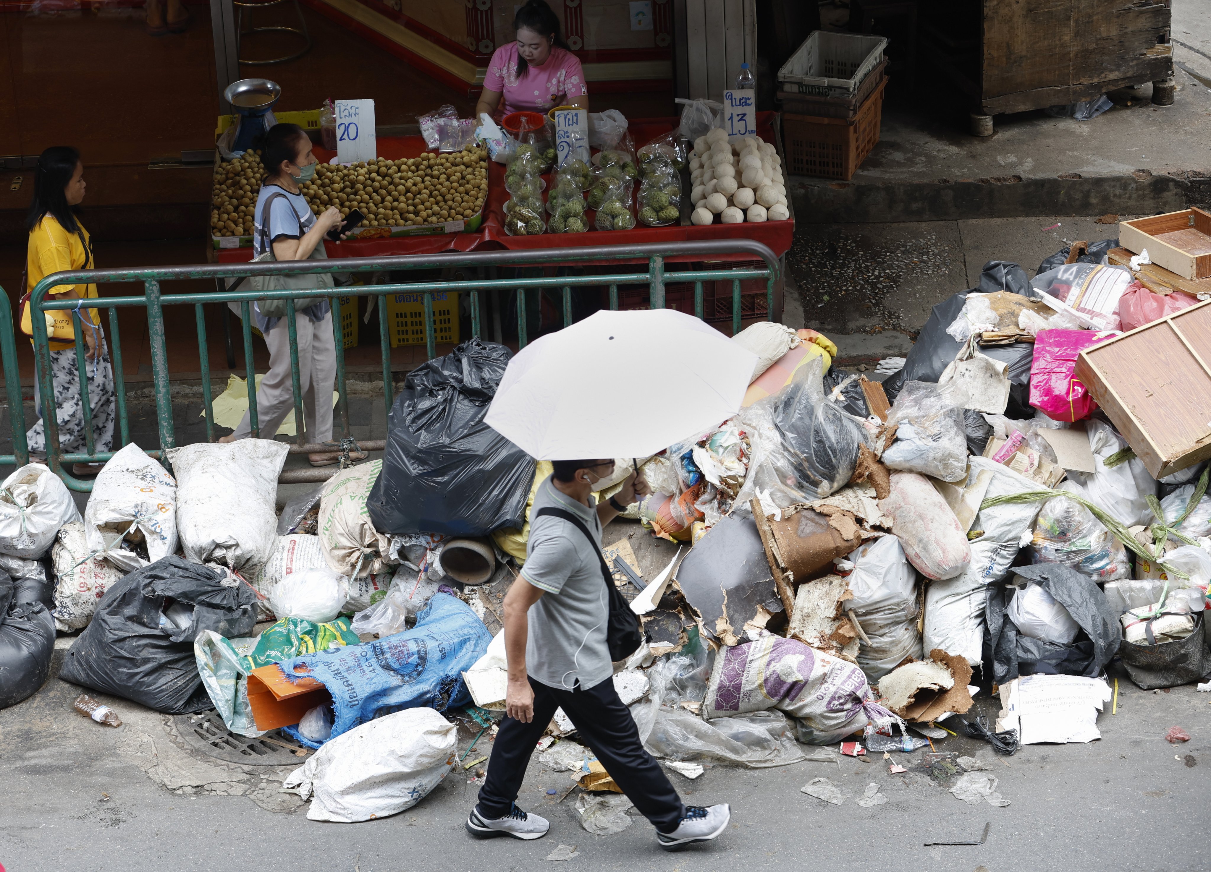 People make their way past a pile of garbage after floodwater receded at a market in Bangkok on Monday. Photo: EPA