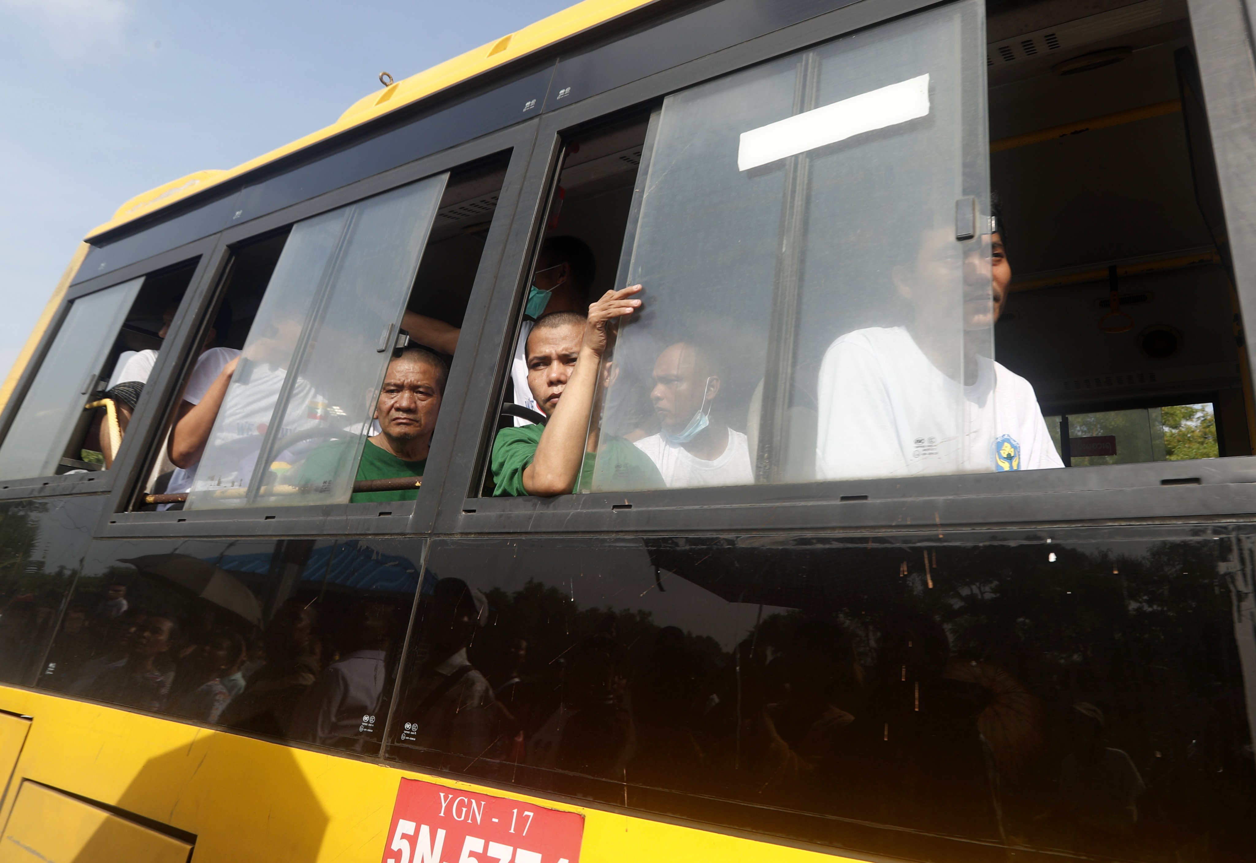 Myanmar men who returned from Malaysia look out from a bus as they leave the Myanmar Navy’s base in Thanlyin on Sunday. Photo: EPA