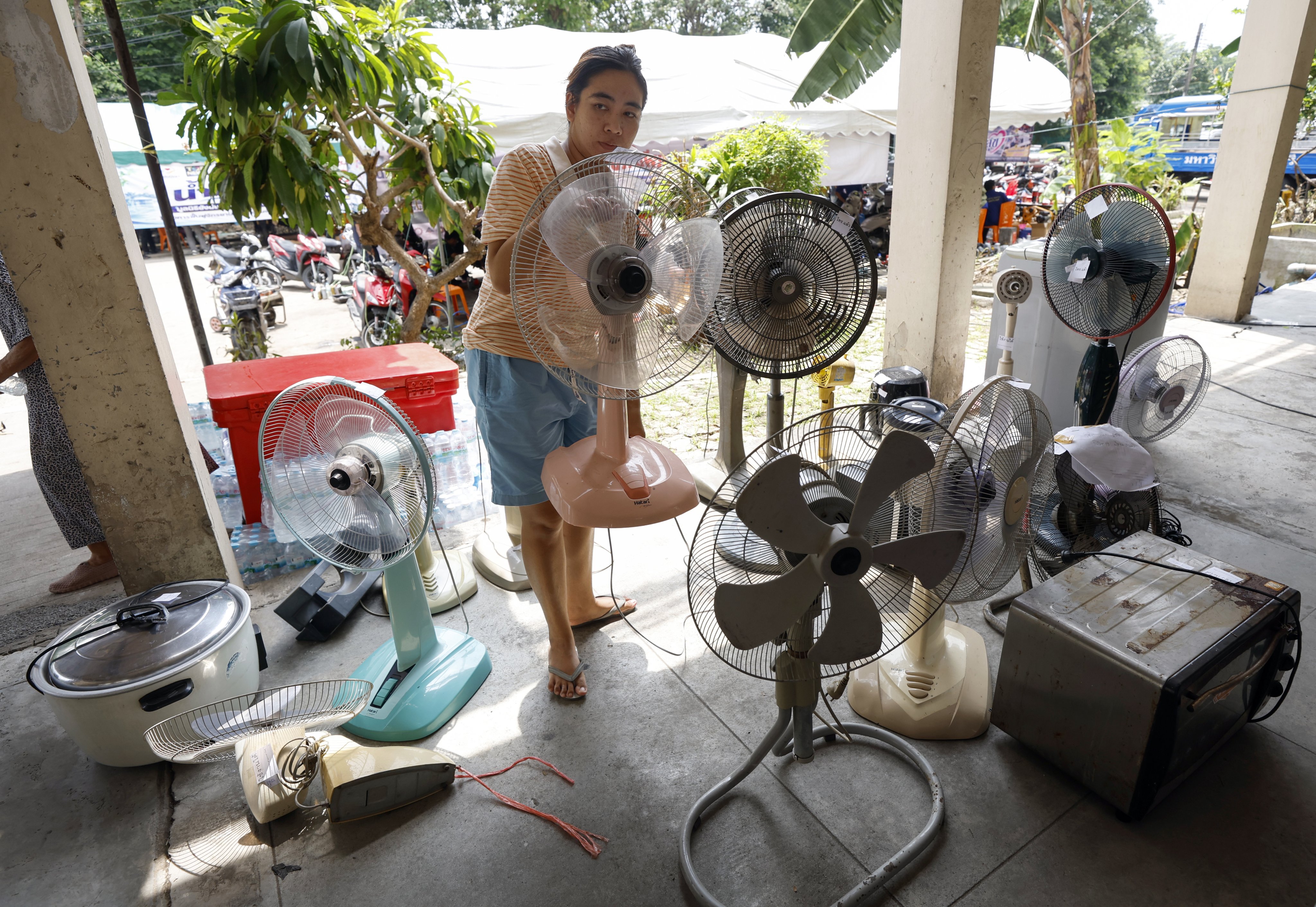 A woman collects a flood-damaged electric fan after it was fixed in a free service for residents in Bangkok on Monday. Photo: EPA