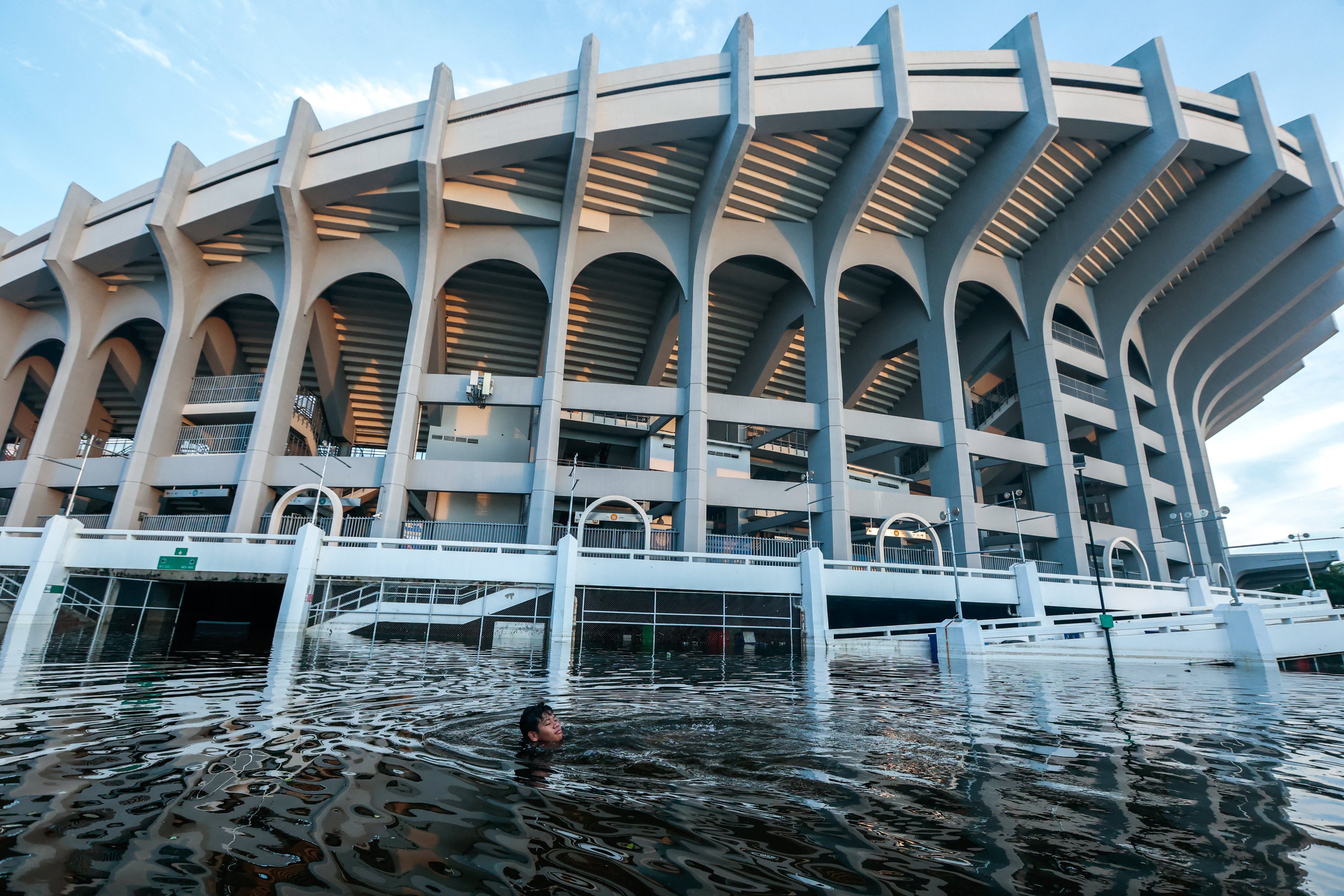 A boy swims in floodwater at the deluged compound of Rajamangala National Stadium following heavy rain in Bangkok, Thailand, on September 29. Photo: Reuters