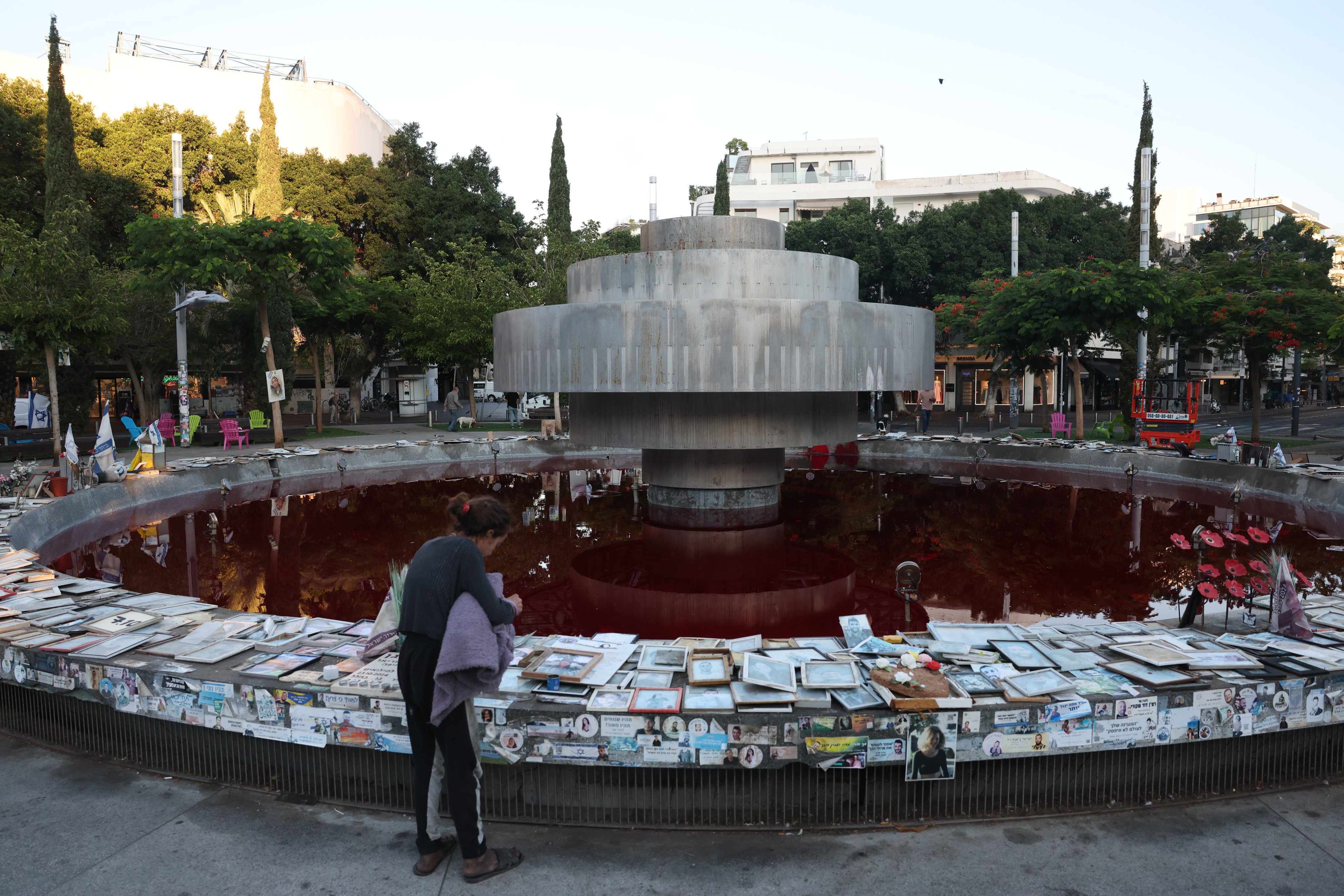 A visitor pauses at a memorial surrounding the Dizengoff Square fountain - dyed red by anti-government protesters - in Tel Aviv. Photo: EPA