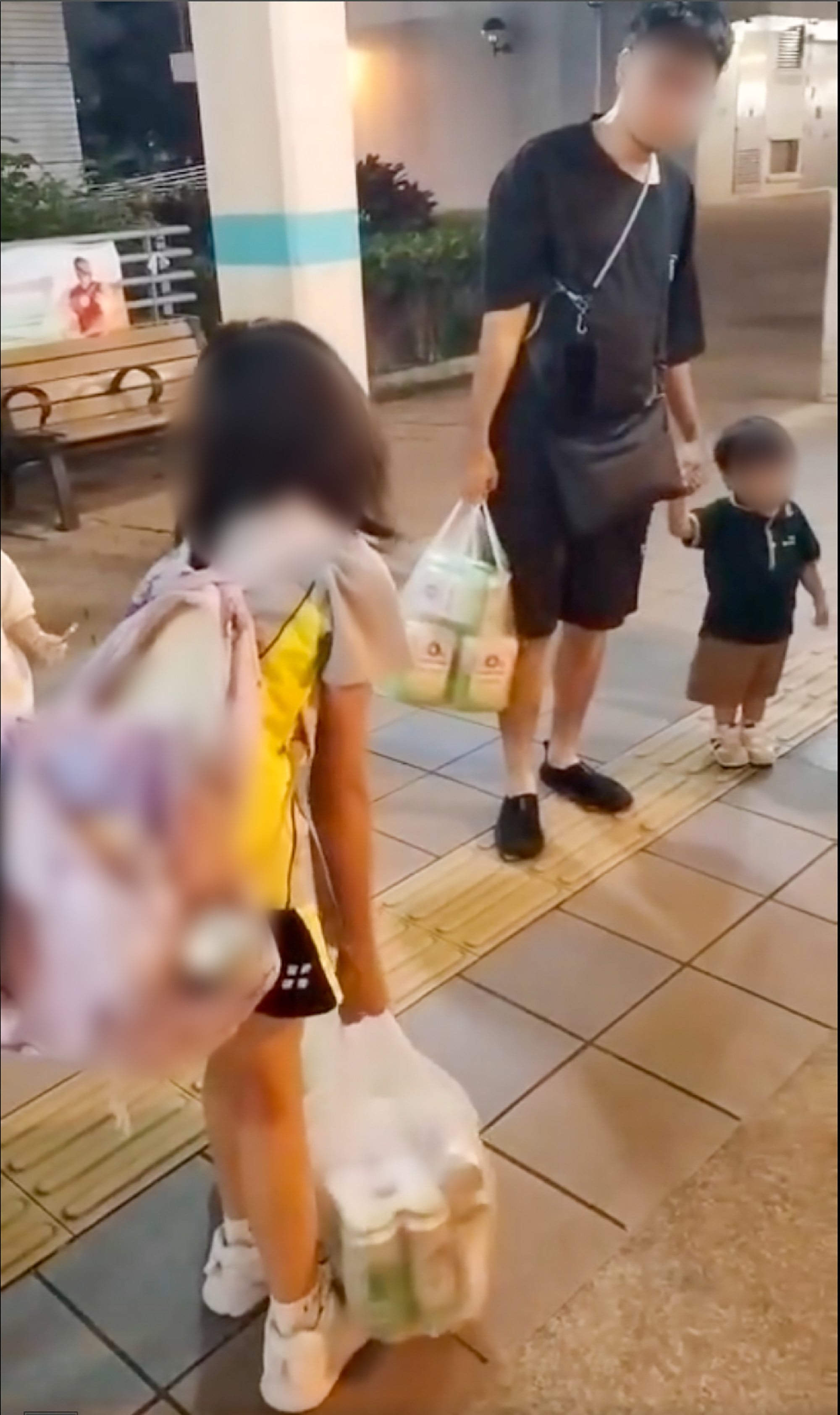 A screenshot from one of the videos posted on social media shows the 10-year-old girl carrying two bags of beer, alongside a man and another child. Photo: Facebook/富泰邨 Fu Tai Estate