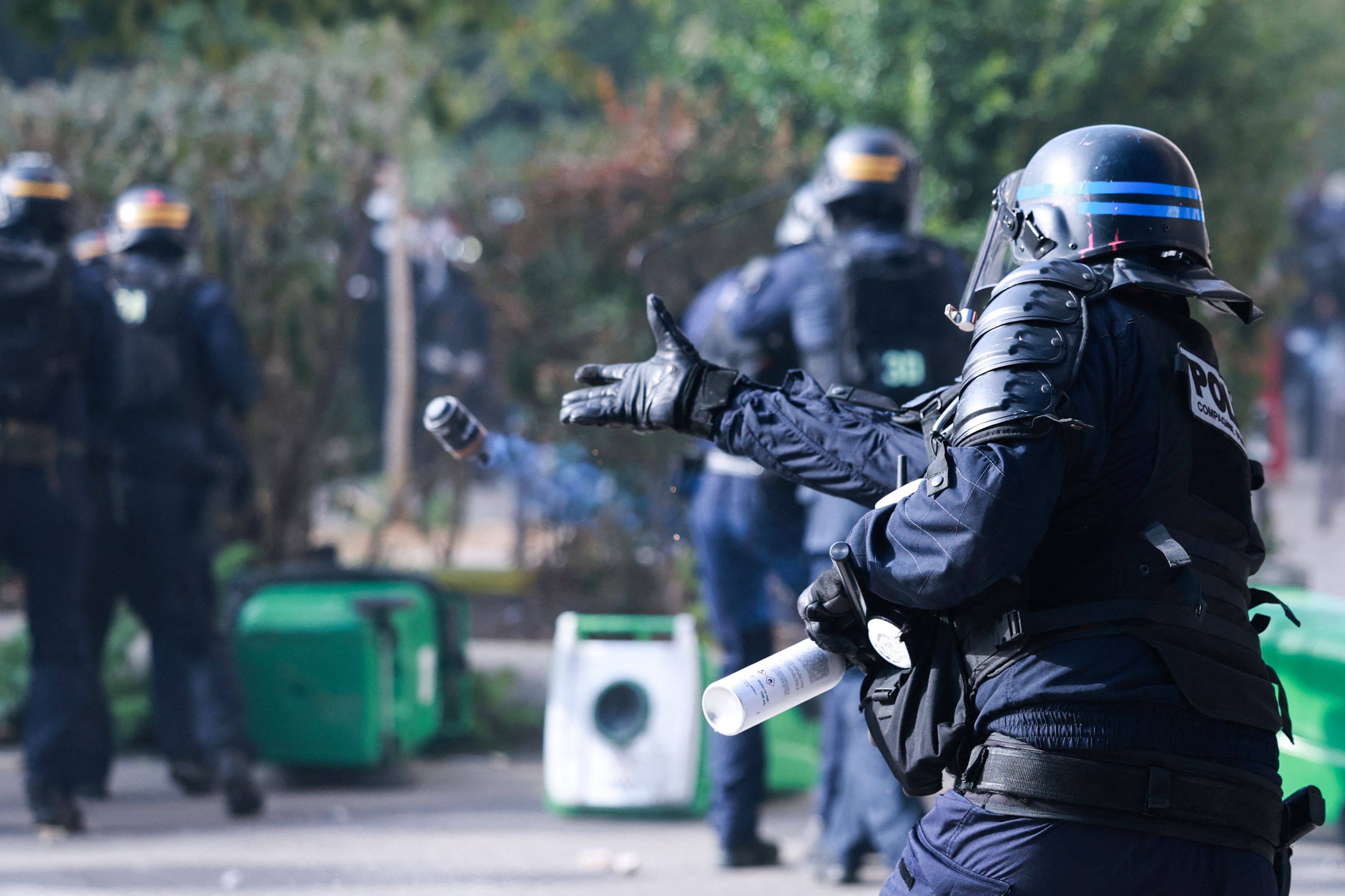 A police officer throws a dispersal grenade during a demonstration of high school students, in Paris on Tuesday. Photo: AFP