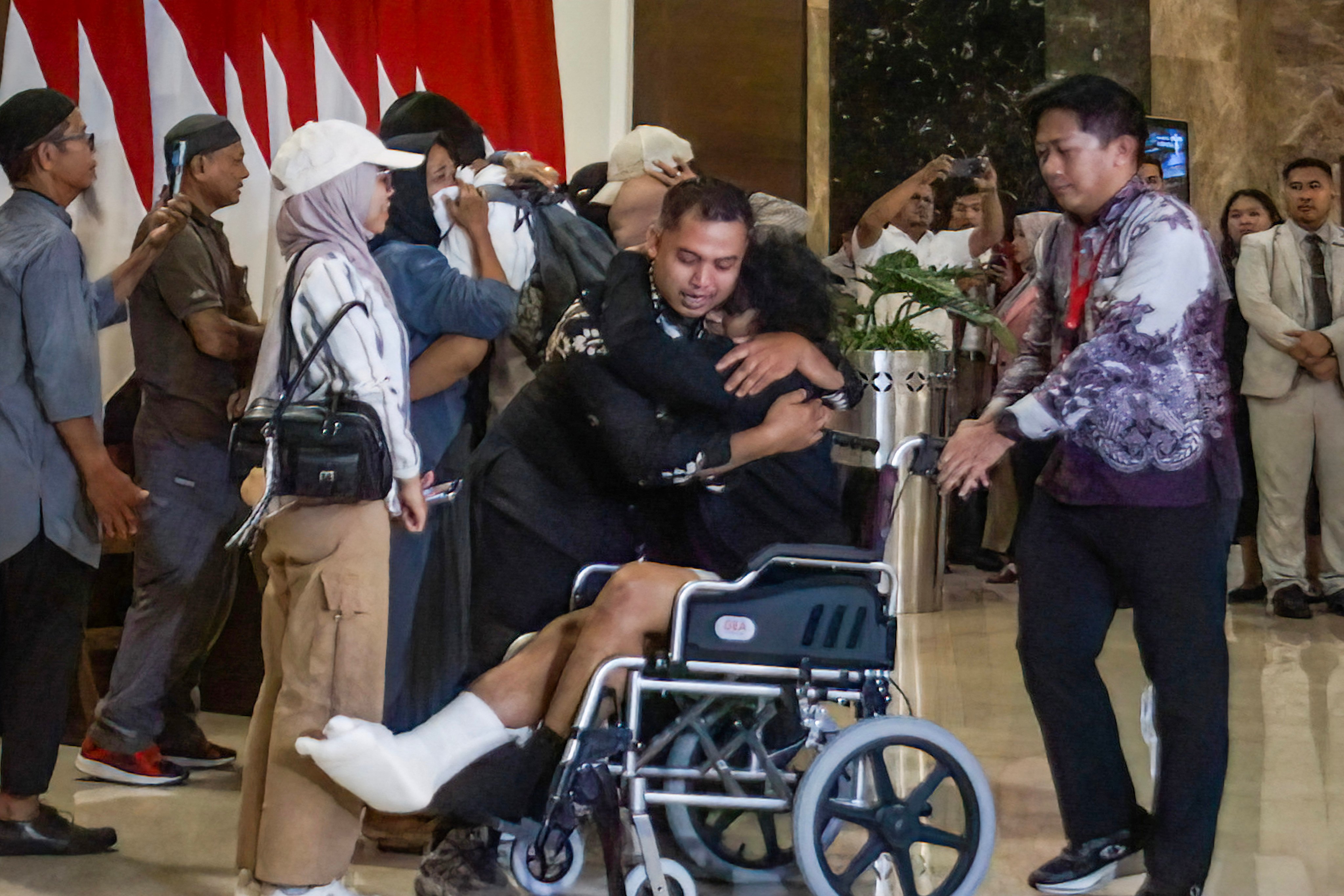 A returned Indonesian seaman (C, in wheelchair) is greeted by his loved ones upon his arrival at Soekarno-Hatta International Airport in Tangerang, Banten, on October 6, 2026, following their release from Somali pirates. Four Indonesian seaman returned home to their families after being held hostage by Somali pirates, with one of them suffering a gunshot wound to the leg inflicted by the captors. (Photo by DENNYS / AFP)