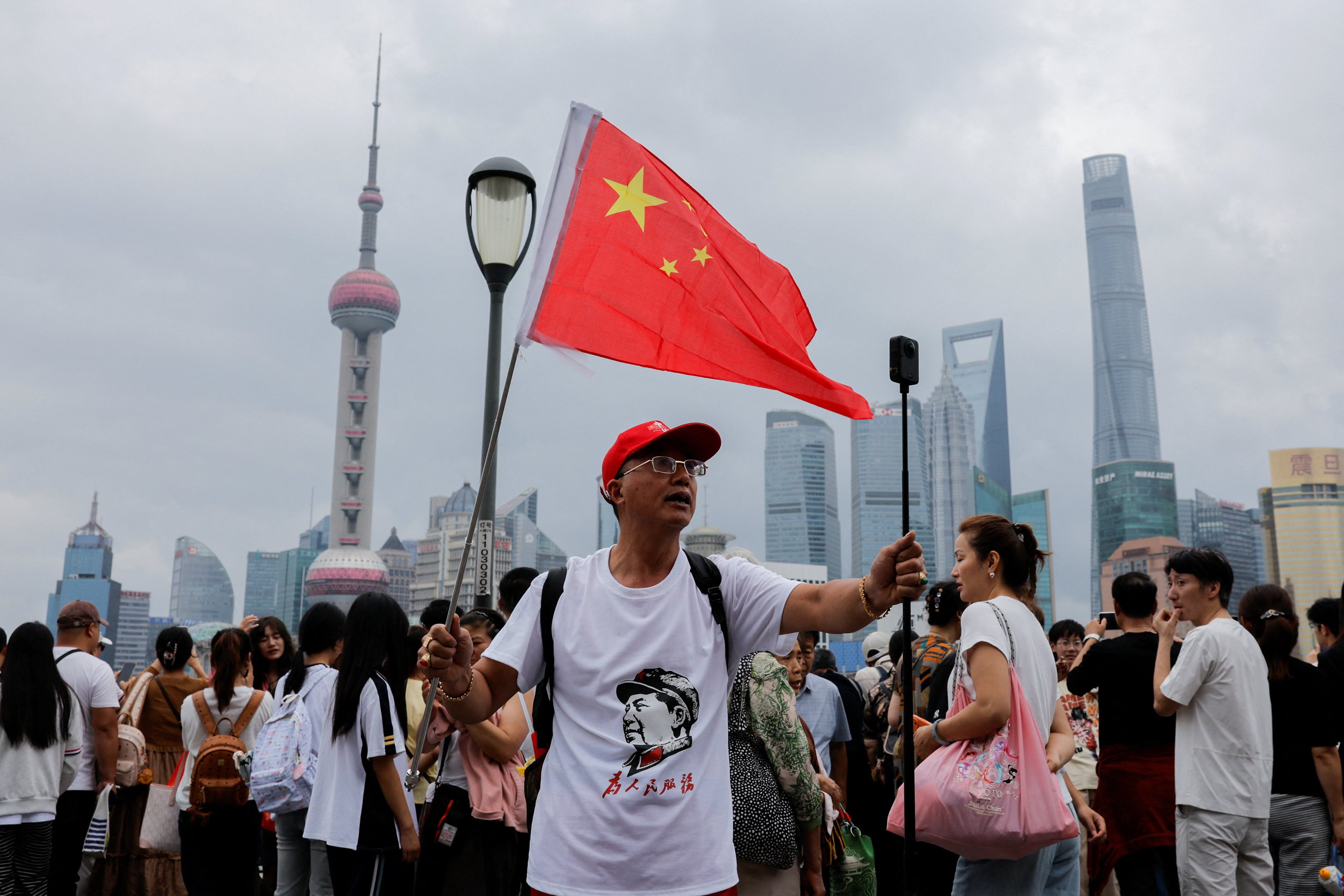 A person waves a Chinese flag while recording a video of himself at Shanghai’s Bund, with the Lujiazui financial district in the background, during China’s National Day on October 1, 2026. Photo: Reuters
