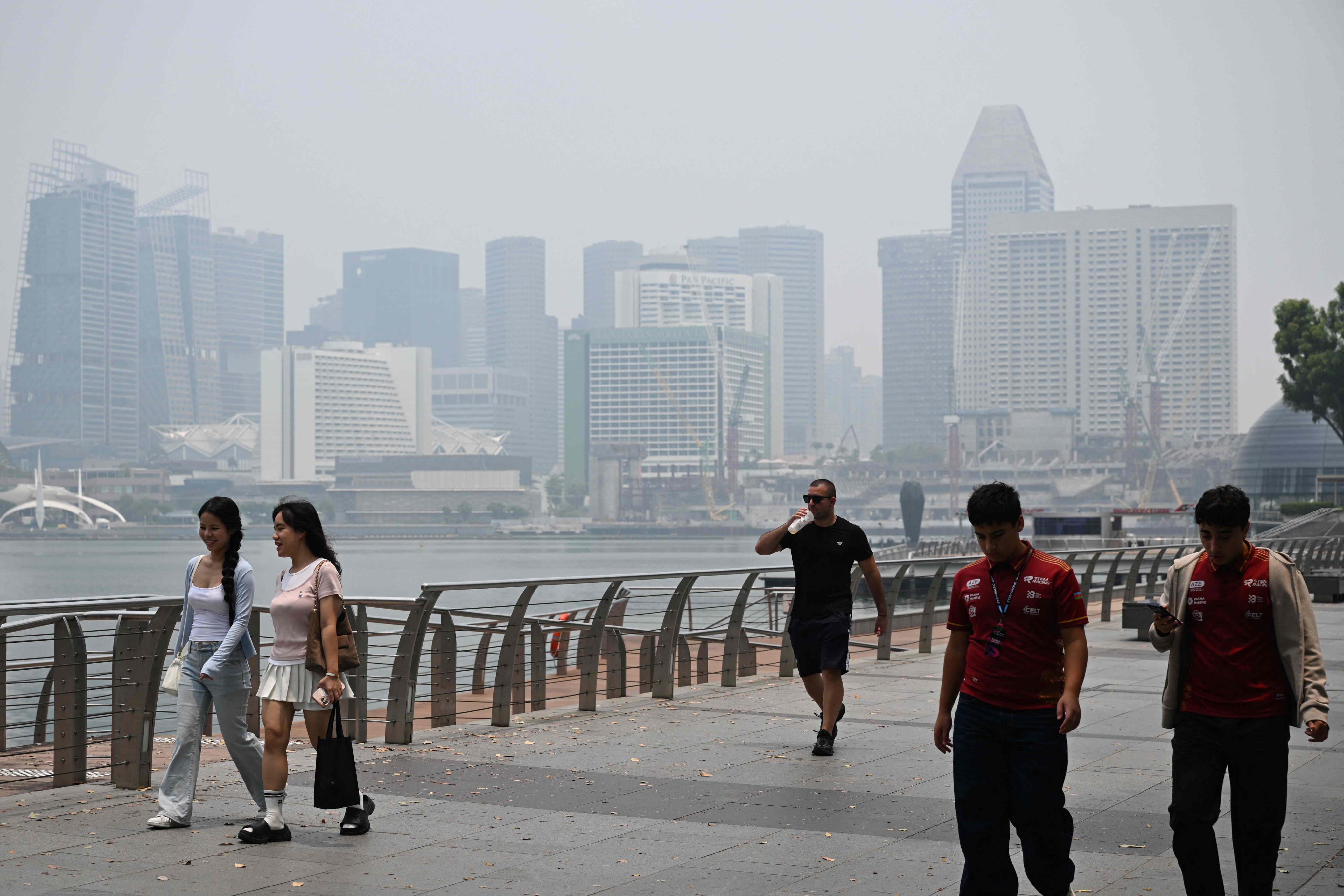 People walk along the boulevard at Marina Bay as buildings are seen shrouded with haze in Singapore on Tuesday. Photo: AFP