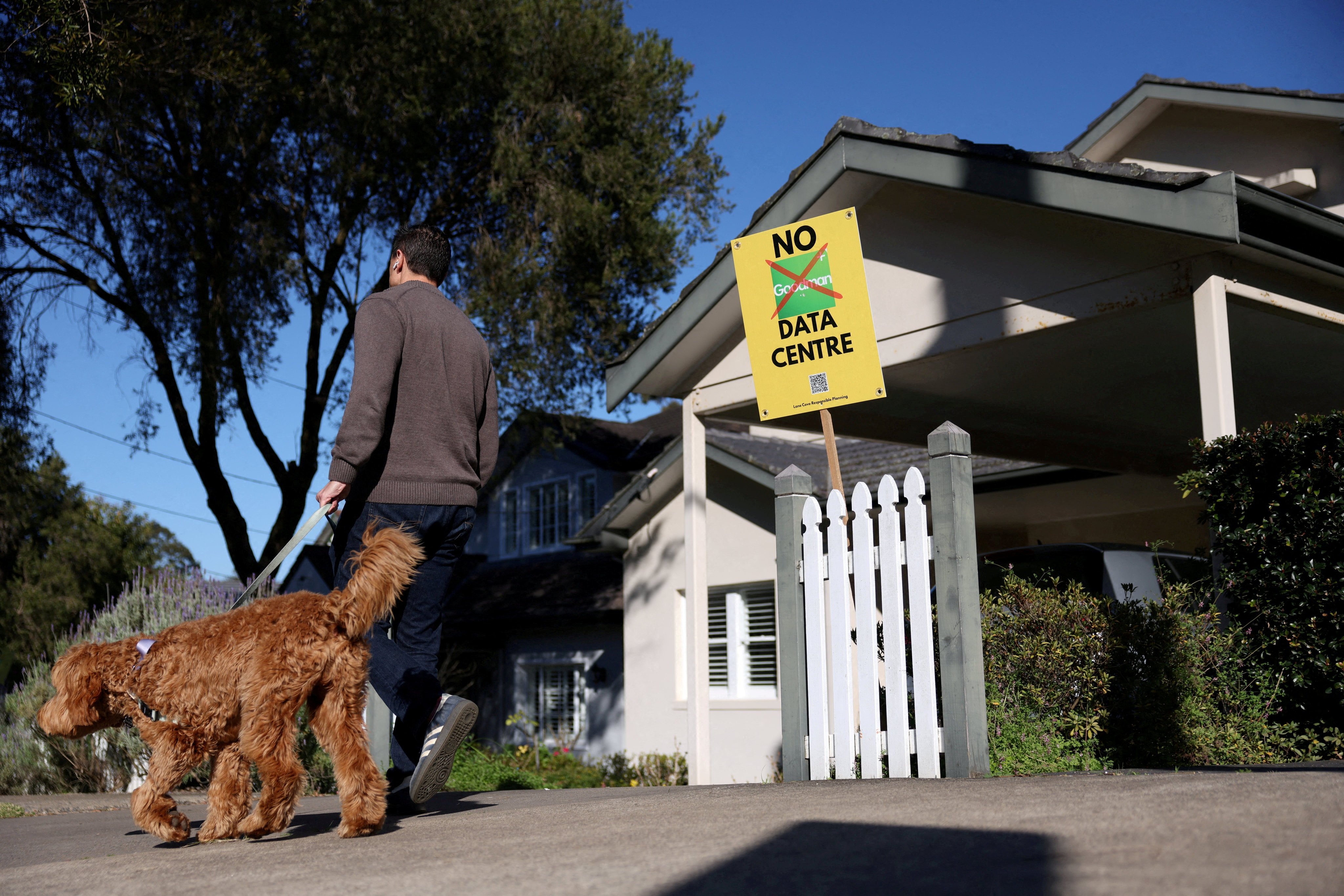 A man walking a dog passes a sign that says “No Goodman Data Centre” outside a home in Sydney, Australia, on August 14. Photo: Reuters