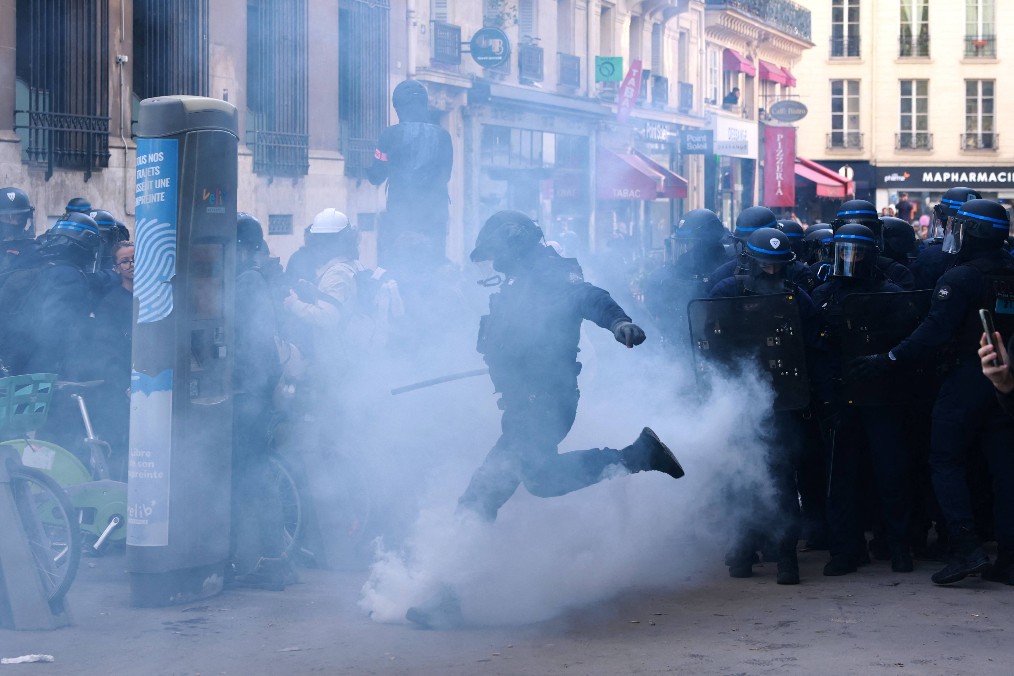 A French police officer kicks a tear gas canister during a demonstration of school pupils at Place de la Bastille in Paris on Thursday. Photo: AFP