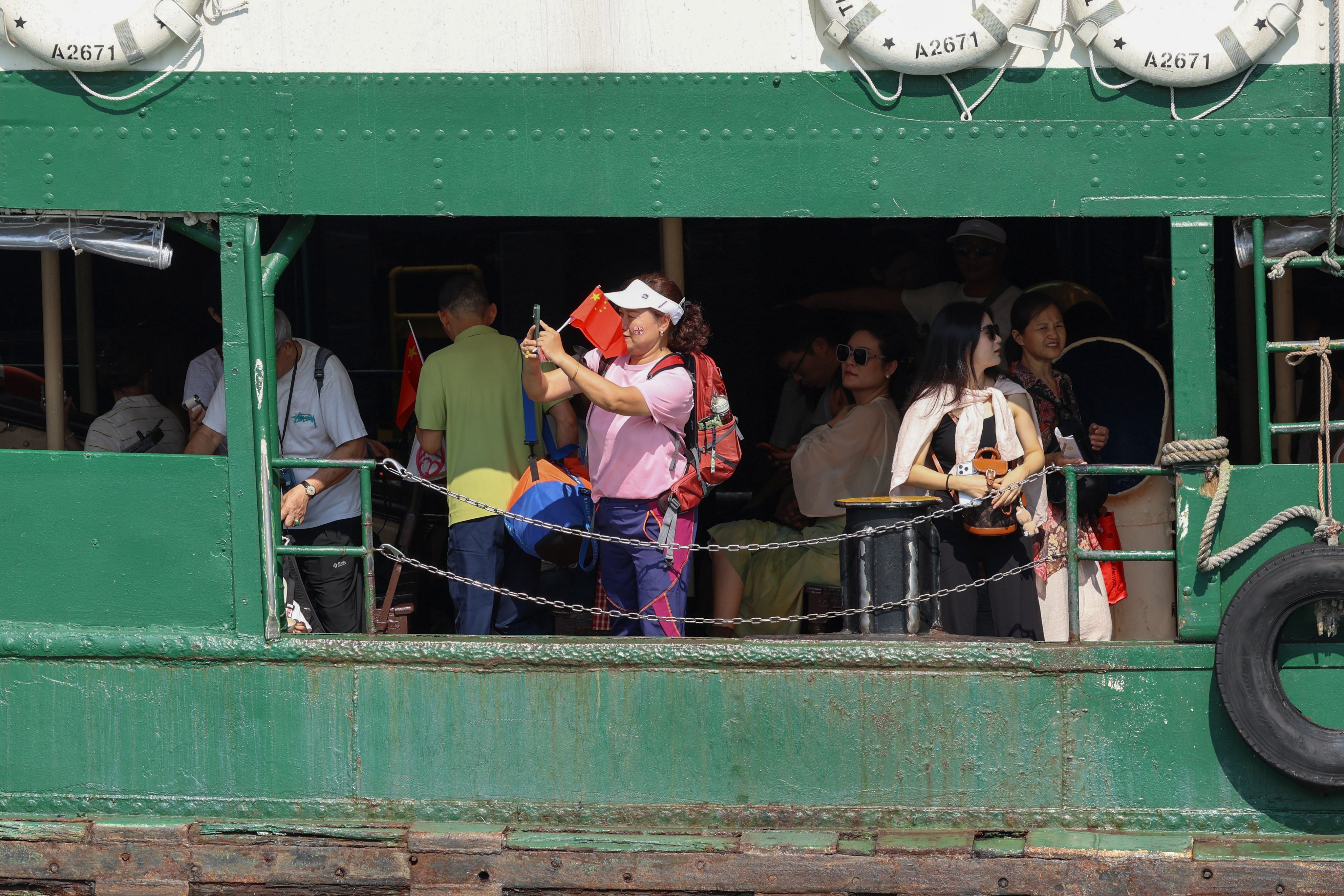 A woman on a ferry takes a picture while holding a Chinese flag in Hong Kong on October 1. Photo: EPA