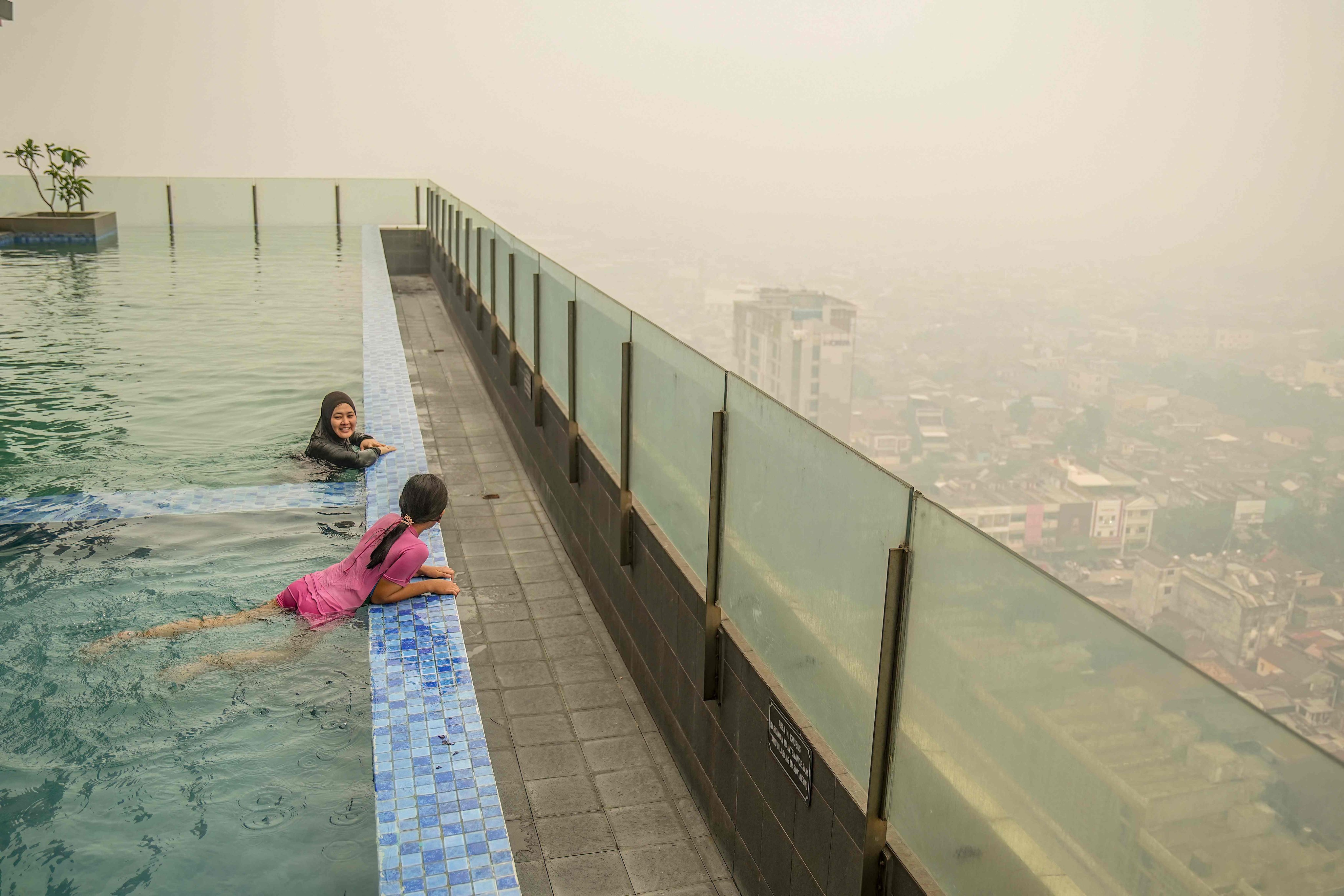Hotel guests swim in a rooftop pool overlooking a cityscape blanketed by thick haze in Palembang, Indonesia’s South Sumatra province, on Thursday. Photo: AFP