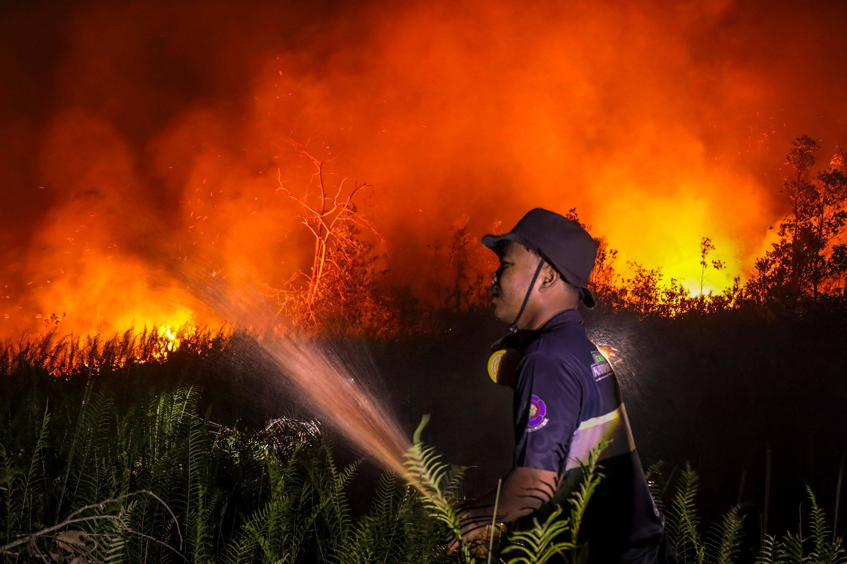 An Indonesian firefighter sprays water to extinguish a raging wildfire in Palangkaraya, Central Kalimantan province, on Thursday. Photo: AFP
