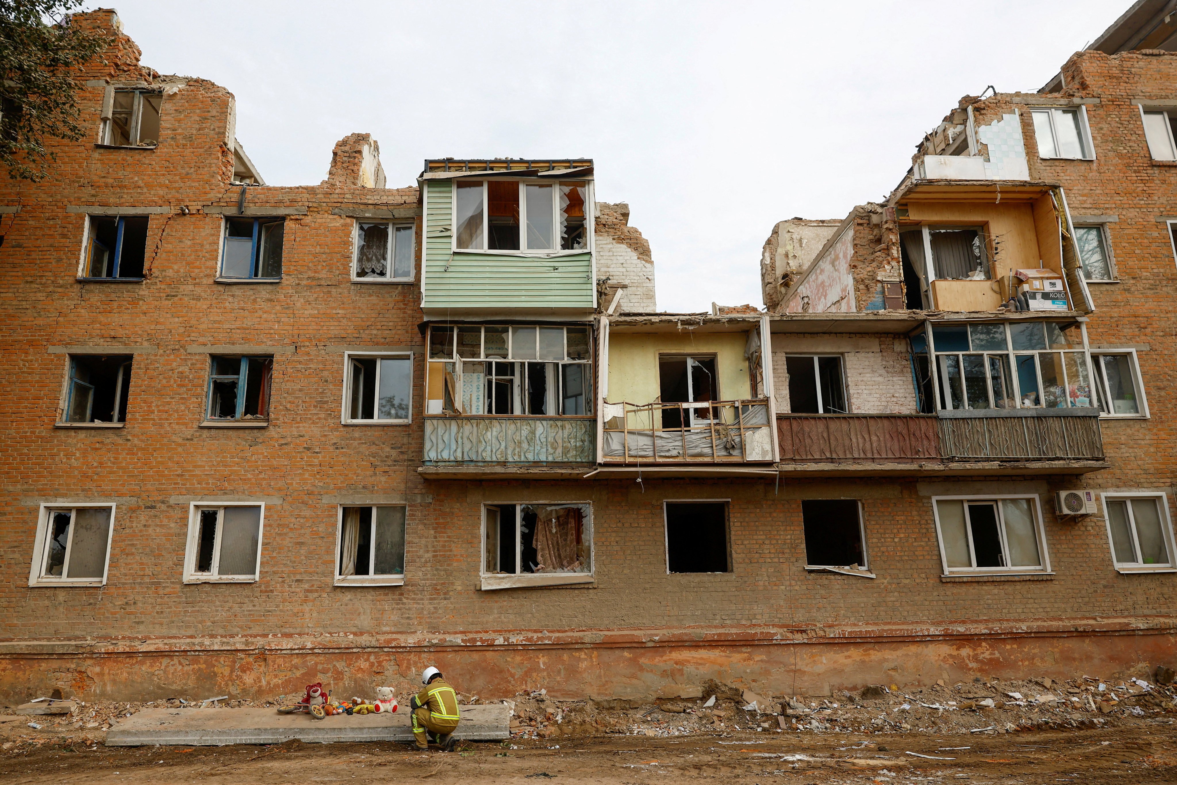 A rescuer kneels next to a makeshift memorial at the site of a residential building hit by a Russian missile strike in the town of Pryluky. Photo: Reuters
